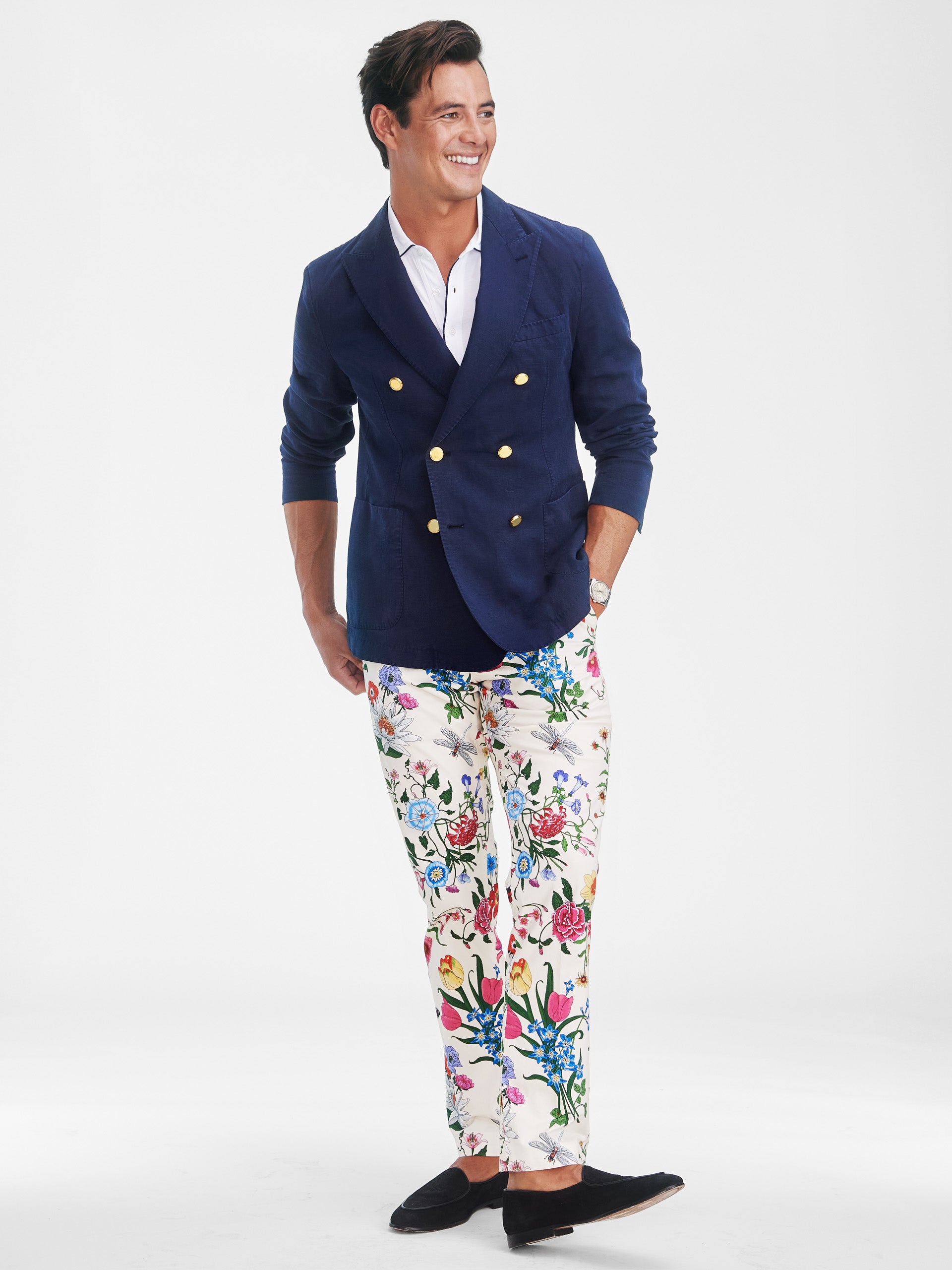 Man wearing a navy Mark Sport Coat by J.McLaughlin paired with floral patterned pants and black slip-on shoes, showcasing effortlessly stylish and enduring designs in innovative fabrics.