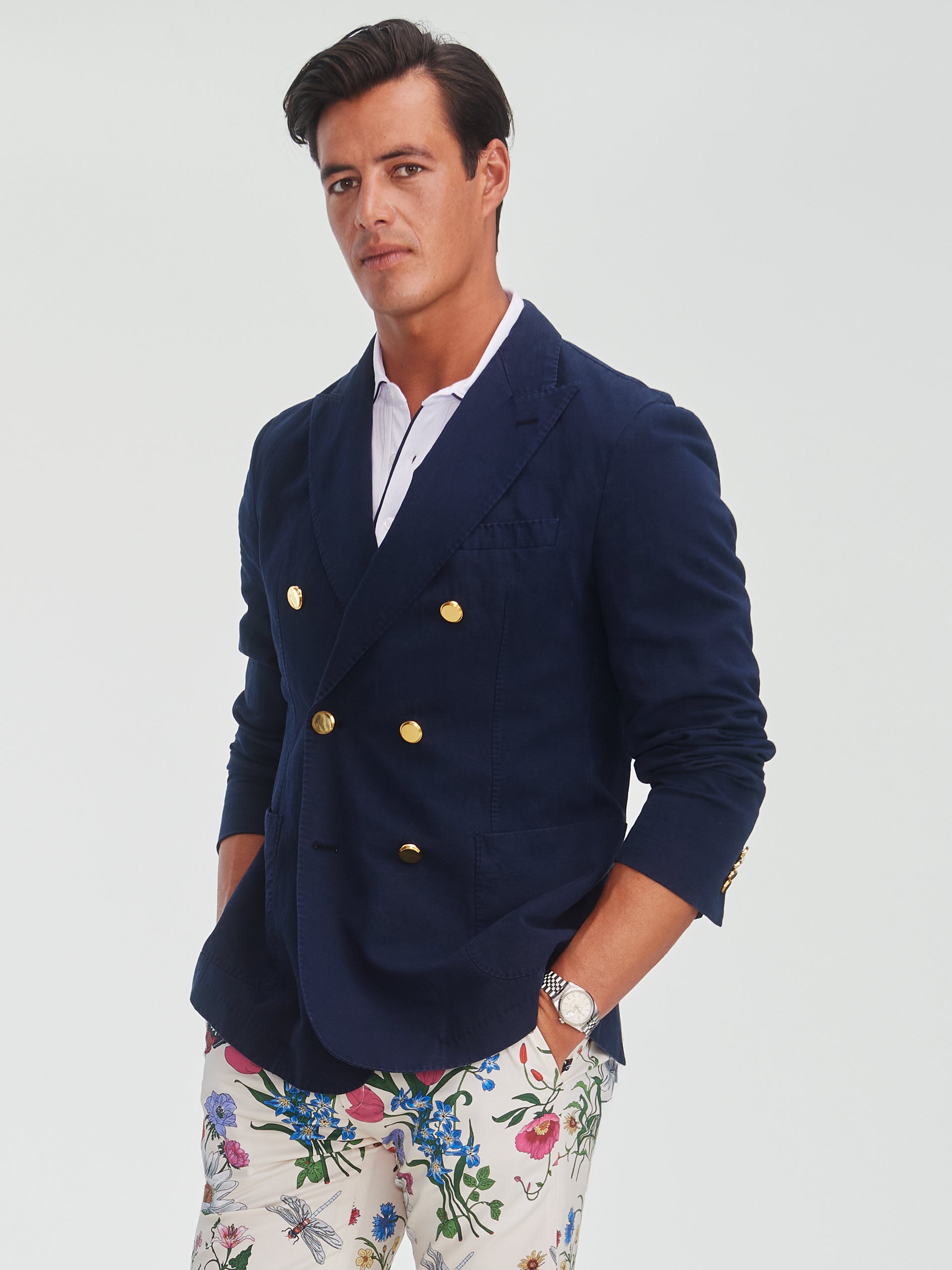A confident man wearing a navy Mark Sport Coat by J.McLaughlin paired with floral patterned pants, showcasing effortlessly stylish, enduring designs and innovative fabrics.