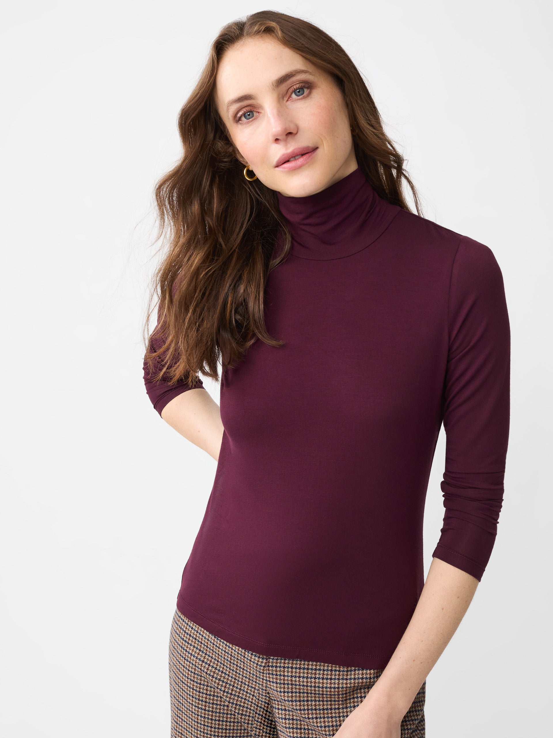 Model wearing J.McLaughlin Nadia turtleneck in burgundy made with rayon/spandex.