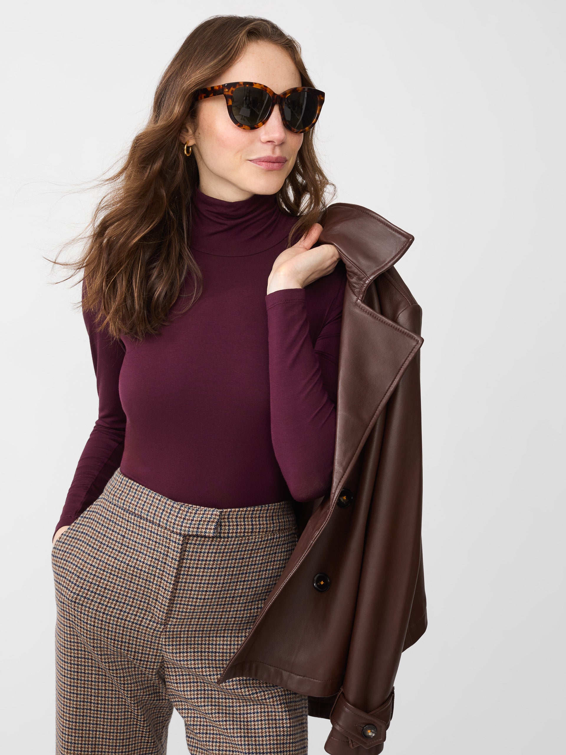 Model wearing J.McLaughlin Nadia turtleneck in burgundy made with rayon/spandex.