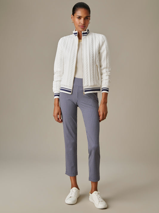 Woman wearing a white textured jacket with striped collar and cuffs paired with J.McLaughlin Newport Capri Pants in Vine and white sneakers, showcasing timeless style.