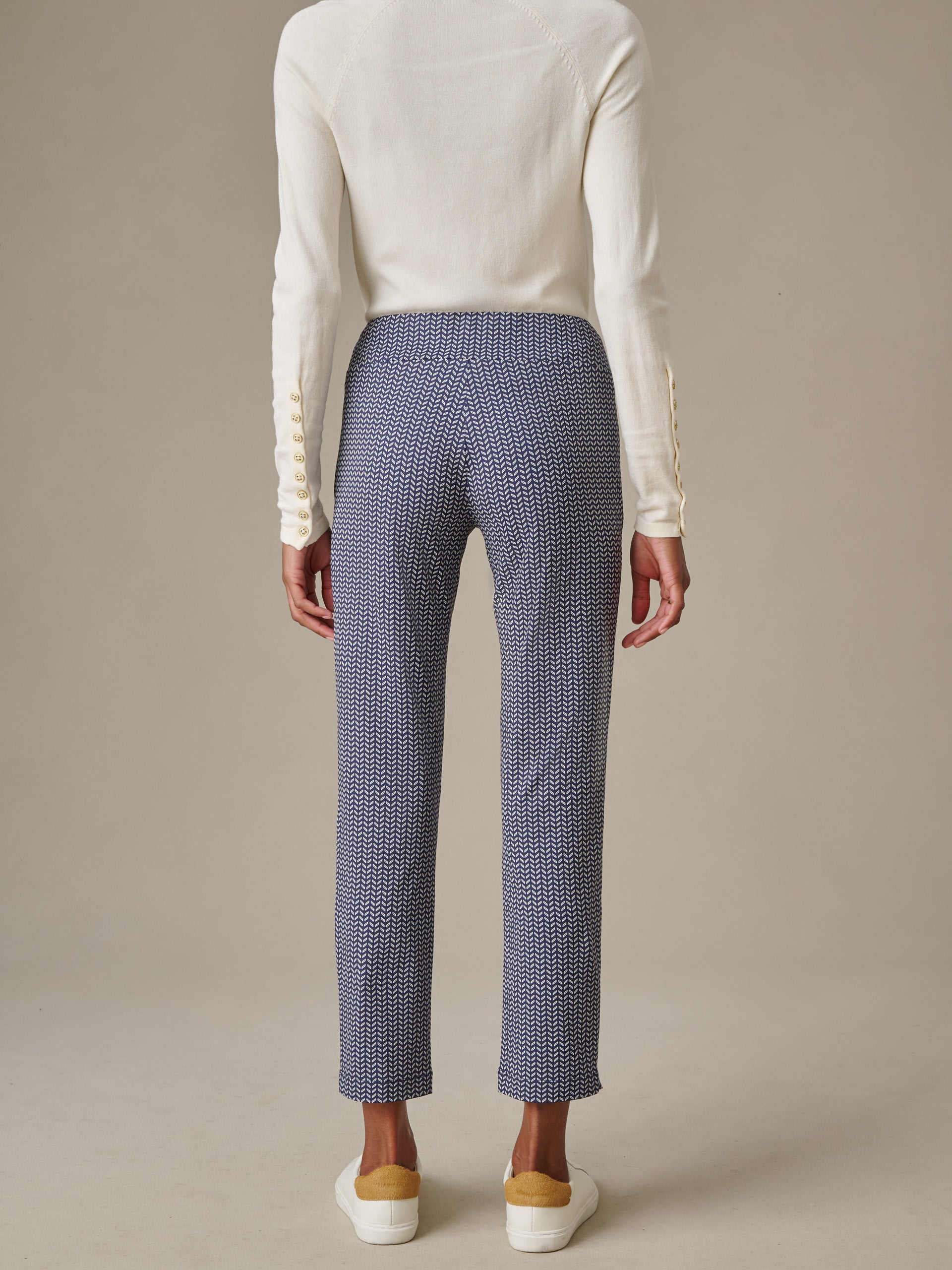 Back view of a person wearing Newport Capri Pants in Vine by J.McLaughlin paired with a white long-sleeve top and white sneakers, showcasing timeless style and enduring design.