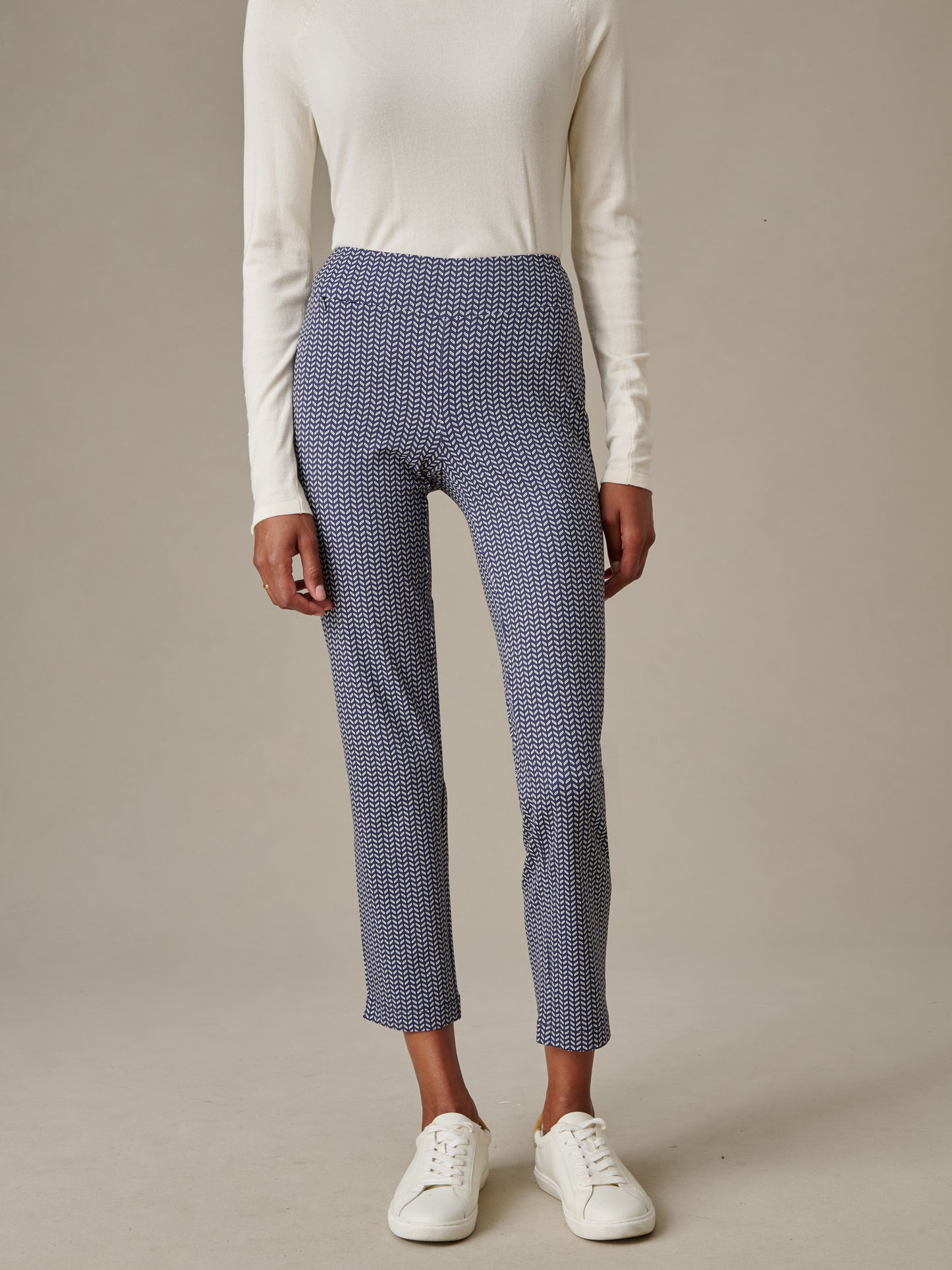 A model wearing Newport Capri Pants in Vine with a white long-sleeve top and white sneakers, showcasing J.McLaughlin’s effortlessly stylish and enduring designs.