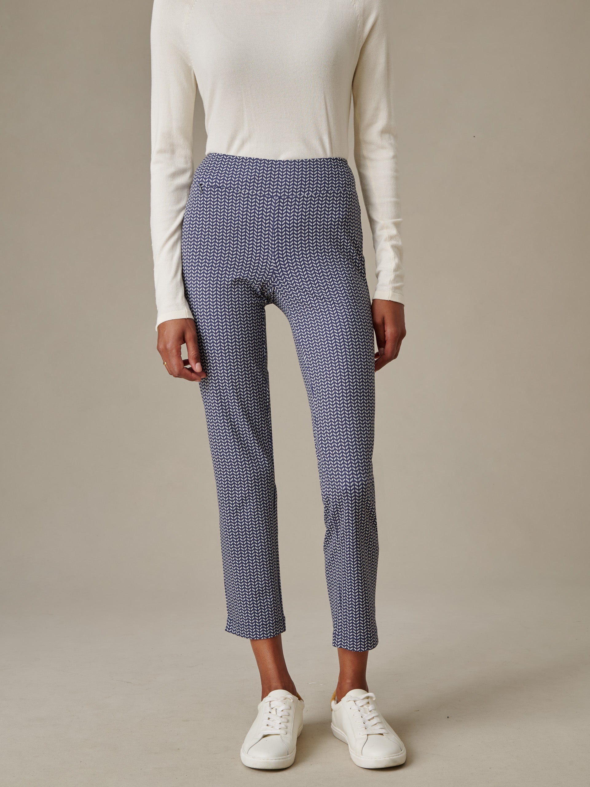 A model wearing Newport Capri Pants in Vine with a white long-sleeve top and white sneakers, showcasing J.McLaughlin’s effortlessly stylish and enduring designs.