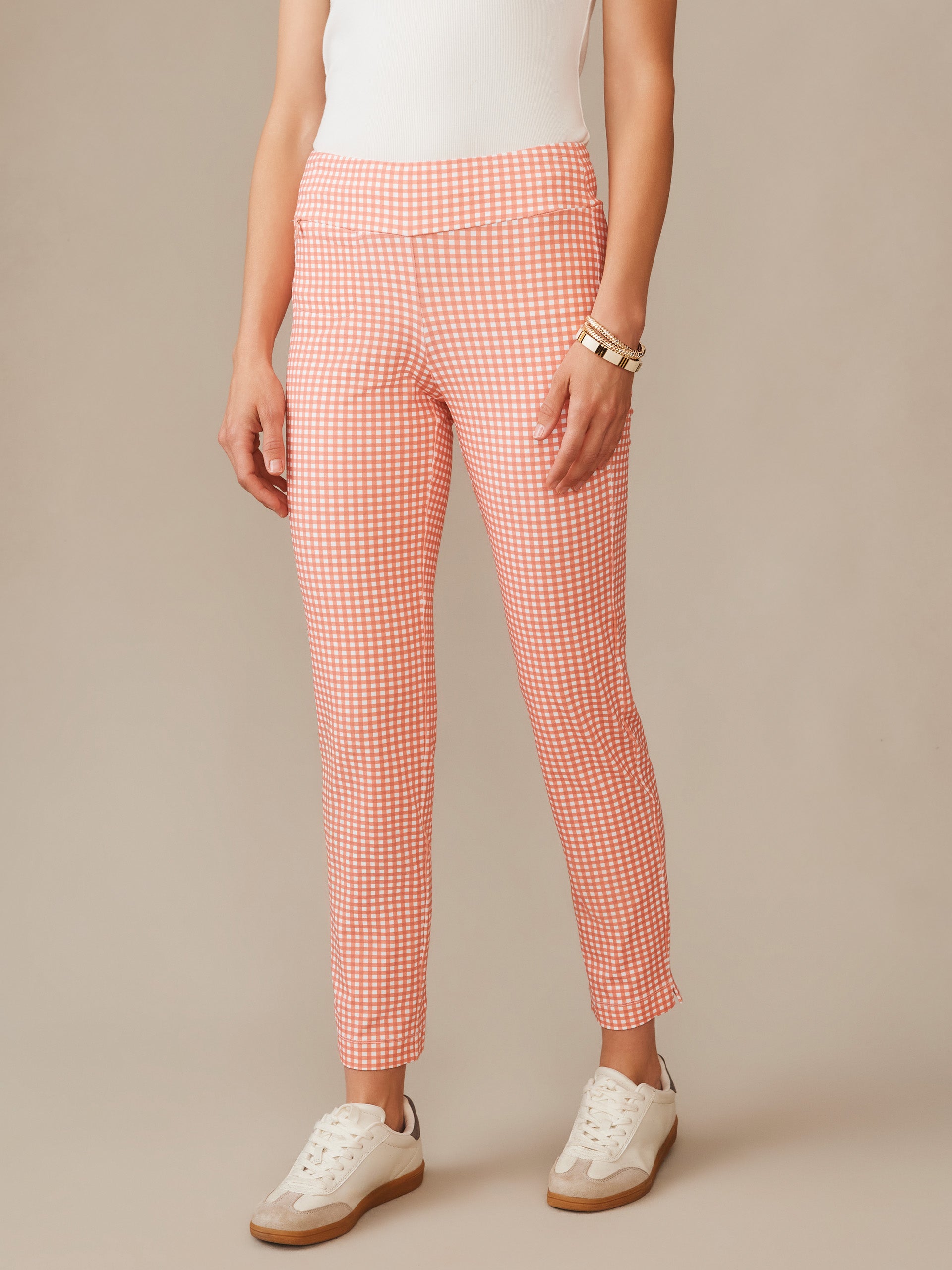 A stylish close-up of a person wearing Newport Capri Pants in Midi Cabana Gingham by J.McLaughlin, featuring a coral and white gingham pattern paired with white sneakers, embodying effortlessly stylish, enduring designs with innovative fabrics for a legacy of timeless fashion. A destination for defining style. Life, Well-Lived.
