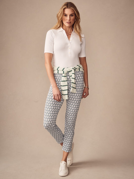 Woman wearing Newport Capri Pants in Signet Lock by J.McLaughlin, styled with a white short-sleeve polo shirt, casual sneakers, and a striped sweater tied around her waist.
