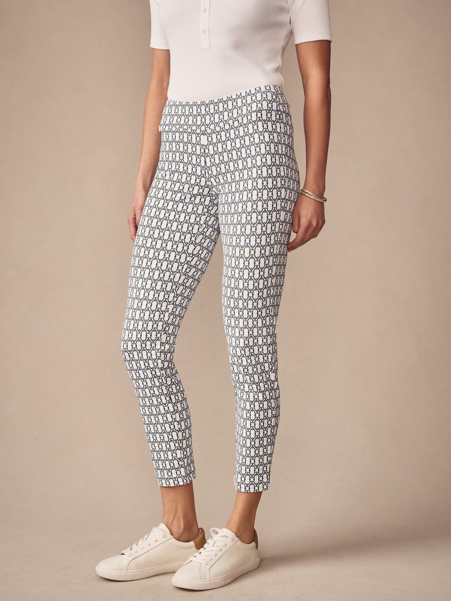 A model wears J.McLaughlin Newport Capri Pants in Signet Lock, featuring a white and blue geometric pattern paired with a white top and white sneakers for a timeless, classic look.