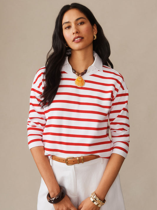 Woman wearing a J.McLaughlin Nico Tee in Stripe with red and white horizontal stripes, styled with white pants, a tan belt, and gold accessories, showcasing effortlessly stylish, enduring designs and innovative fabrics for a legacy of timeless fashion. A destination for defining style. Life, Well-Lived.