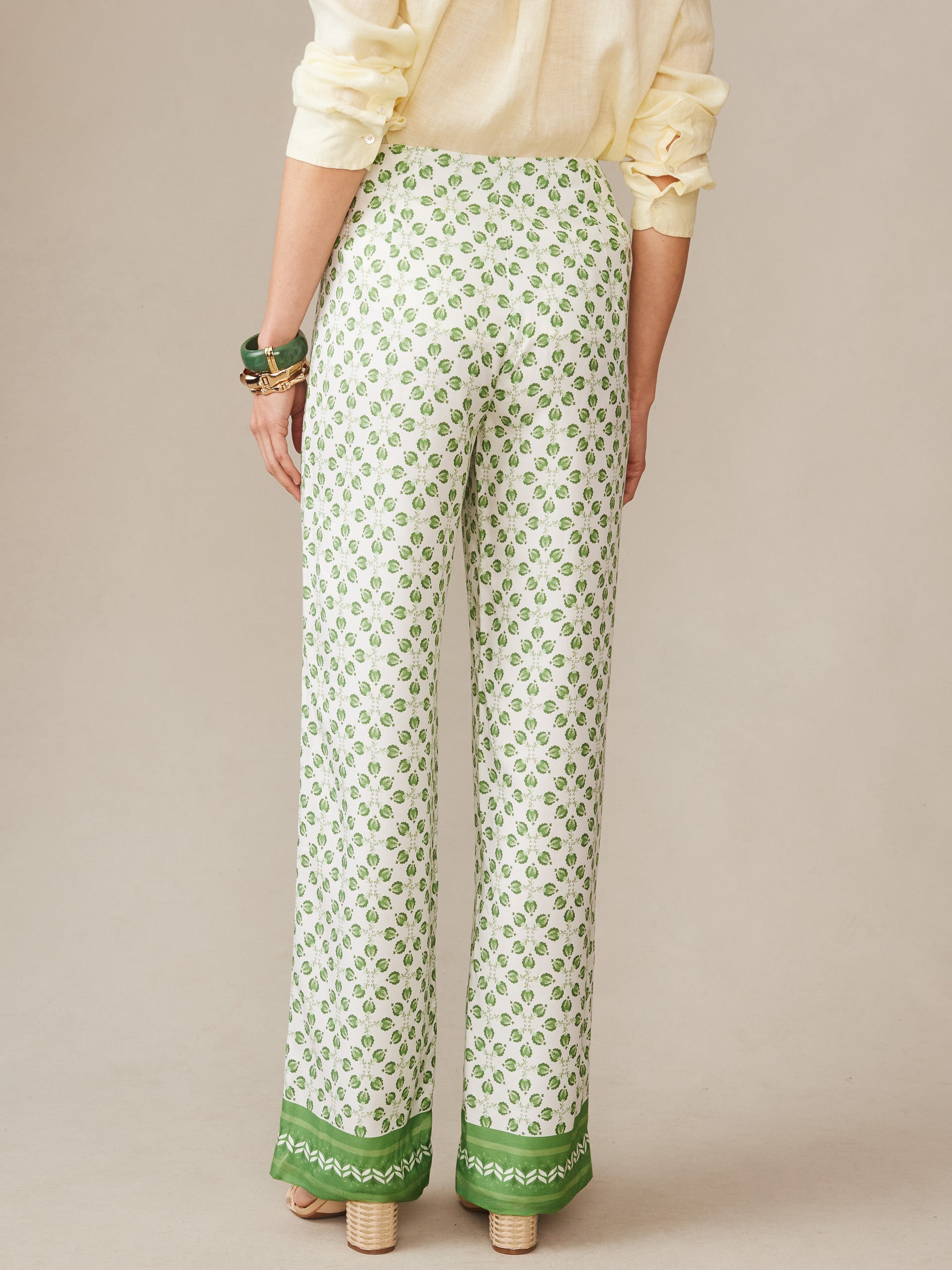 Back view of a woman wearing Carter Silk Blend Pants in Mythic Geo Border by J.McLaughlin, featuring a white and green geometric pattern with green trim, showcasing effortlessly stylish, enduring designs and innovative fabrics from a brand known for a legacy of timeless fashion. A destination for defining style. Life, Well-Lived.