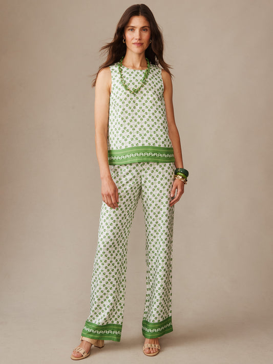 Woman wearing J. McLaughlin Carter Silk Blend Pants in Mythic Geo Border with a matching sleeveless top, styled with green accessories, showcasing effortlessly stylish, enduring designs and innovative fabrics.