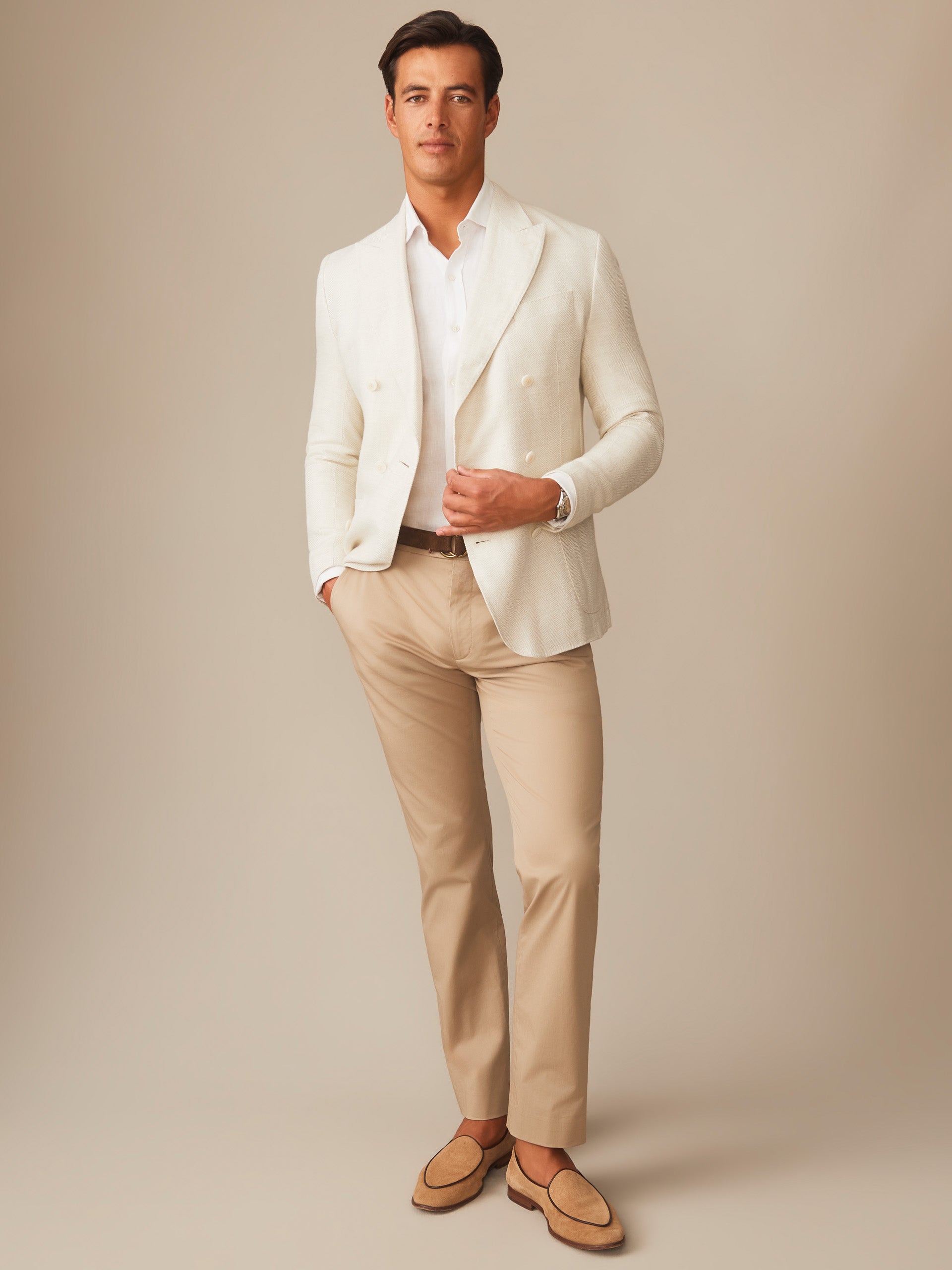 Man wearing a stone Notting Blazer by J.McLaughlin paired with beige pants and loafers, showcasing effortlessly stylish, enduring designs in innovative fabrics from a destination for defining style. Life, Well-Lived.