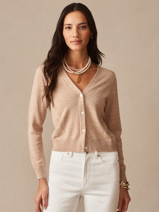 Woman wears an Olivette Cardigan by J.McLaughlin in a soft beige shade paired with white pants, showcasing effortlessly stylish, enduring designs and a legacy of timeless fashion.