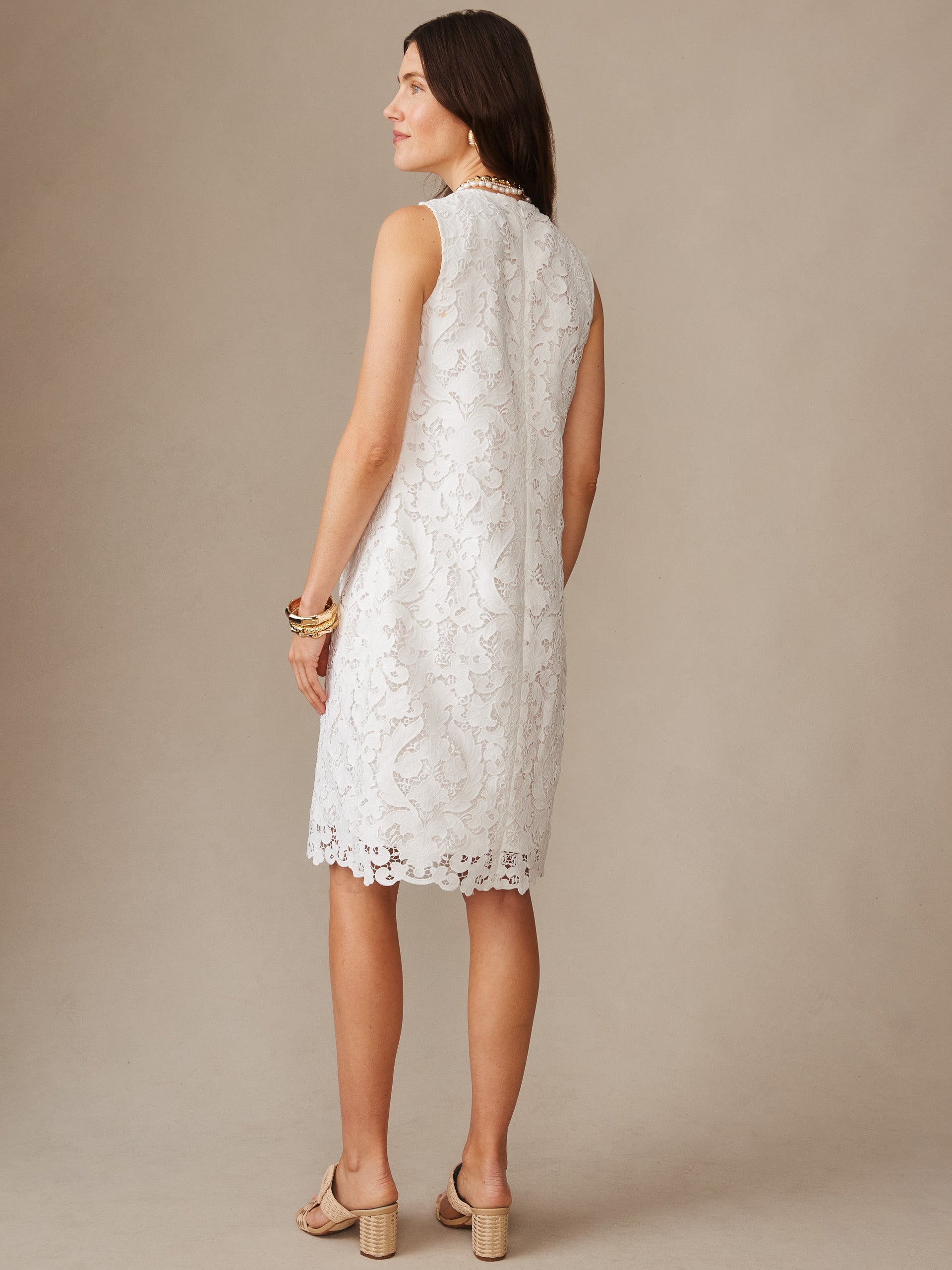 Woman wearing an off-white Olivia Lace Dress by J.McLaughlin featuring intricate lace detailing, sleeveless design, and scalloped hem, showcasing effortlessly stylish, enduring designs with legacy of timeless fashion. A destination for defining style. Life, Well-Lived.