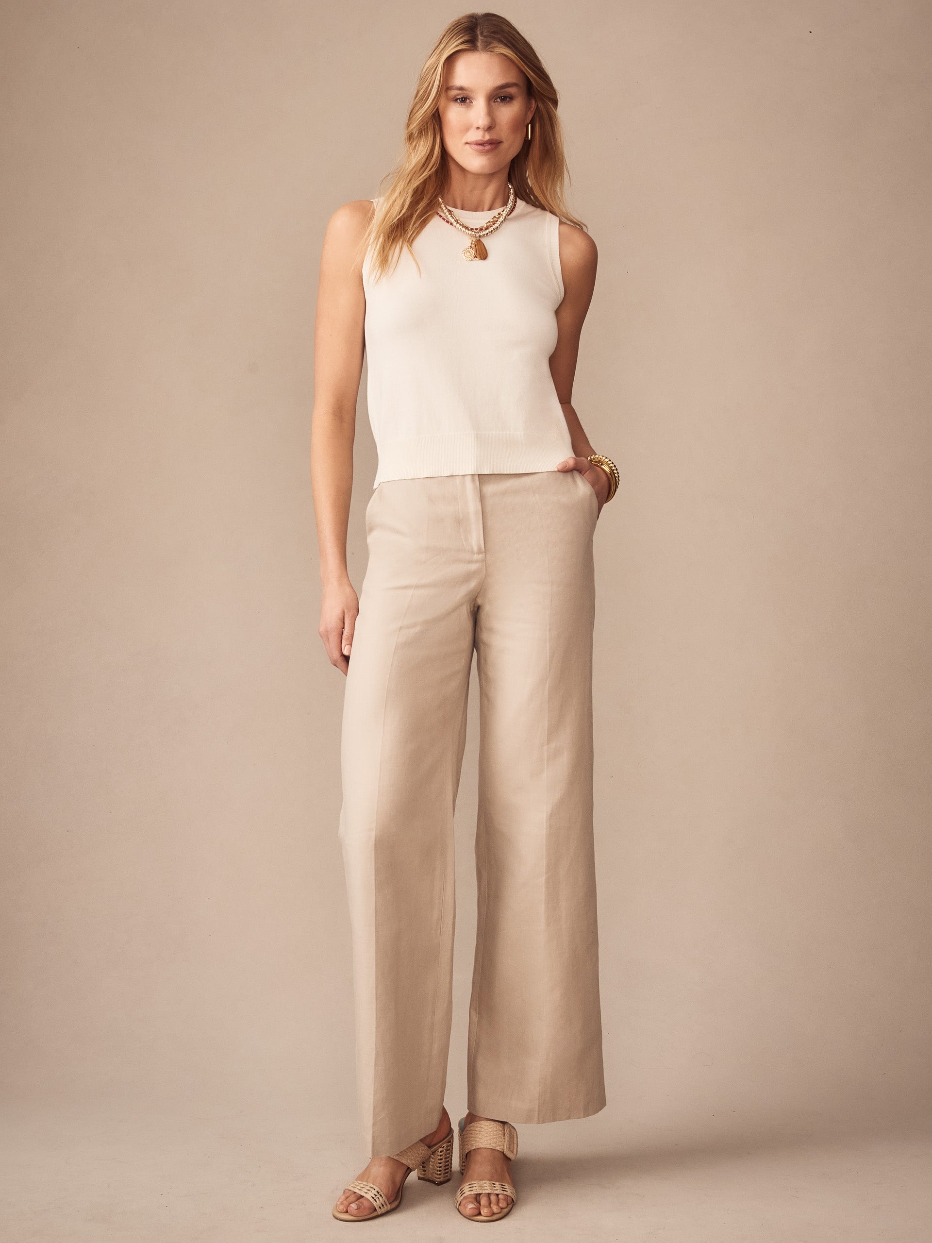 Woman wearing an ivory Opal Sweater Tank by J.McLaughlin paired with beige wide-leg pants and sandals, showcasing effortlessly stylish, enduring designs with a legacy of timeless fashion.