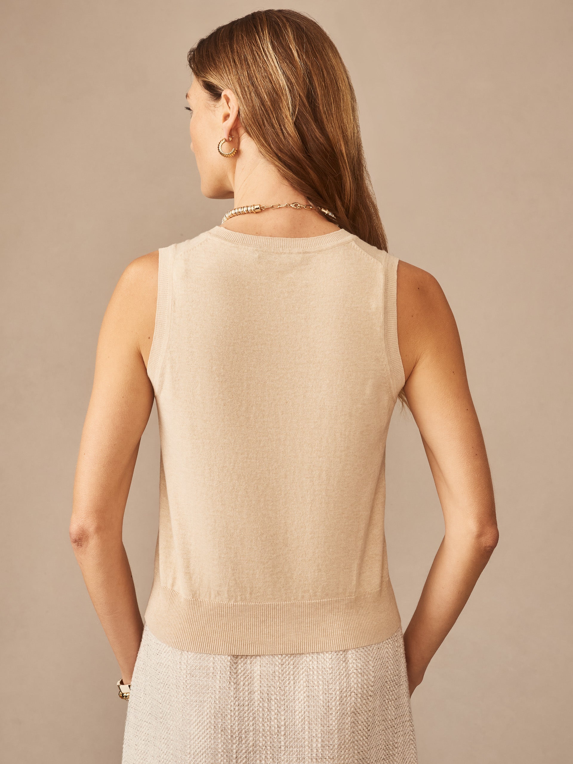 Woman wearing a beige Opal Sweater Tank by J.McLaughlin, showcasing effortlessly stylish and enduring design with innovative fabrics, embodying a legacy of timeless fashion.