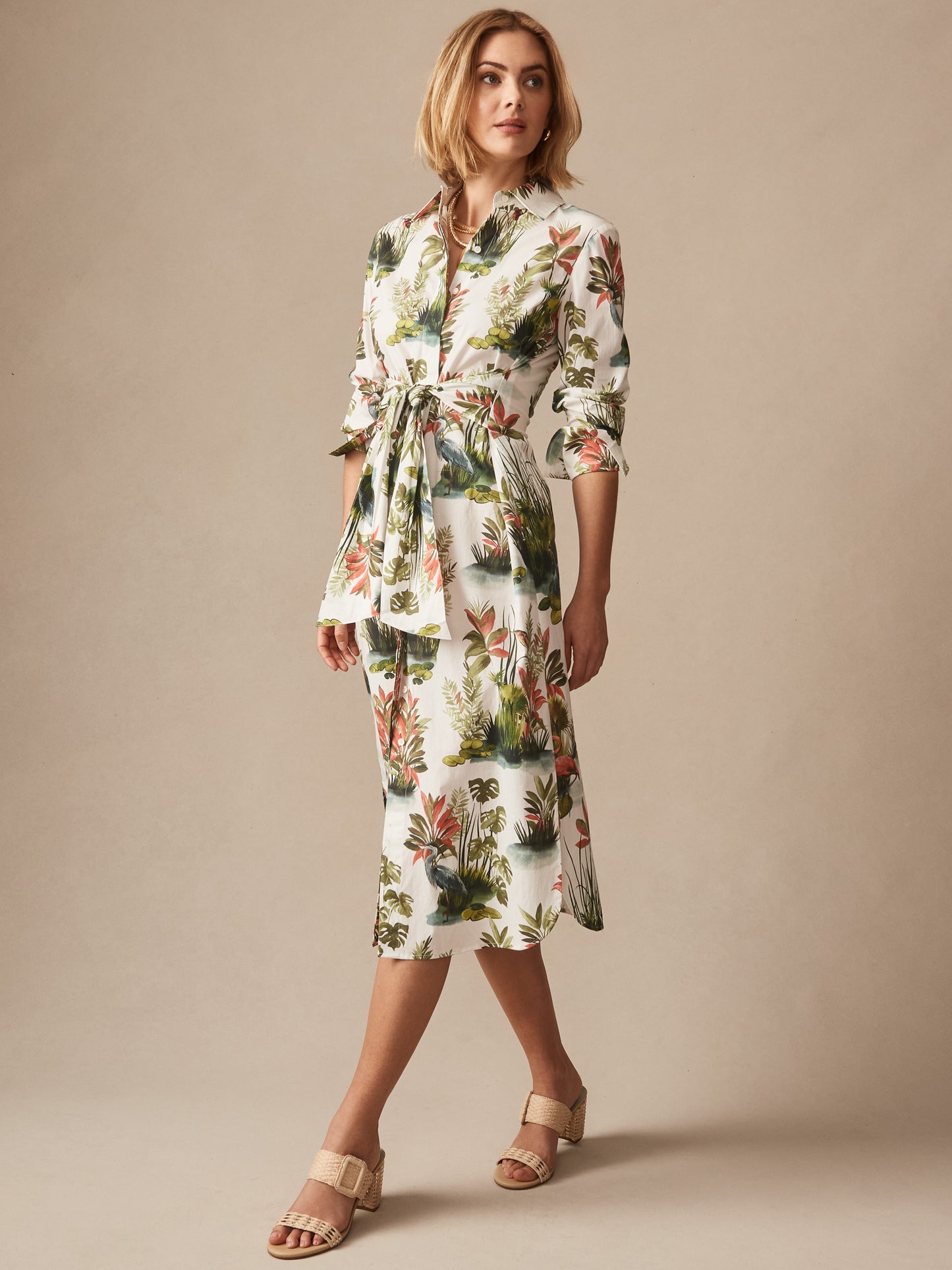 Woman wearing Orla Dress in Tidal Palms by J.McLaughlin featuring a botanical print with green and coral tones, styled with beige sandals, showcasing effortlessly stylish and enduring designs.