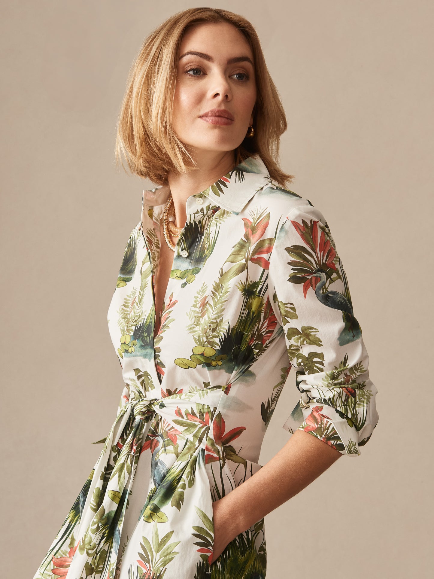 Woman wearing J.McLaughlin Orla Dress in Tidal Palms, a beautifully crafted dress with leafy green, coral, and white botanical print, showcasing effortlessly stylish, enduring designs in innovative fabrics. A destination for defining style. Life, Well-Lived.