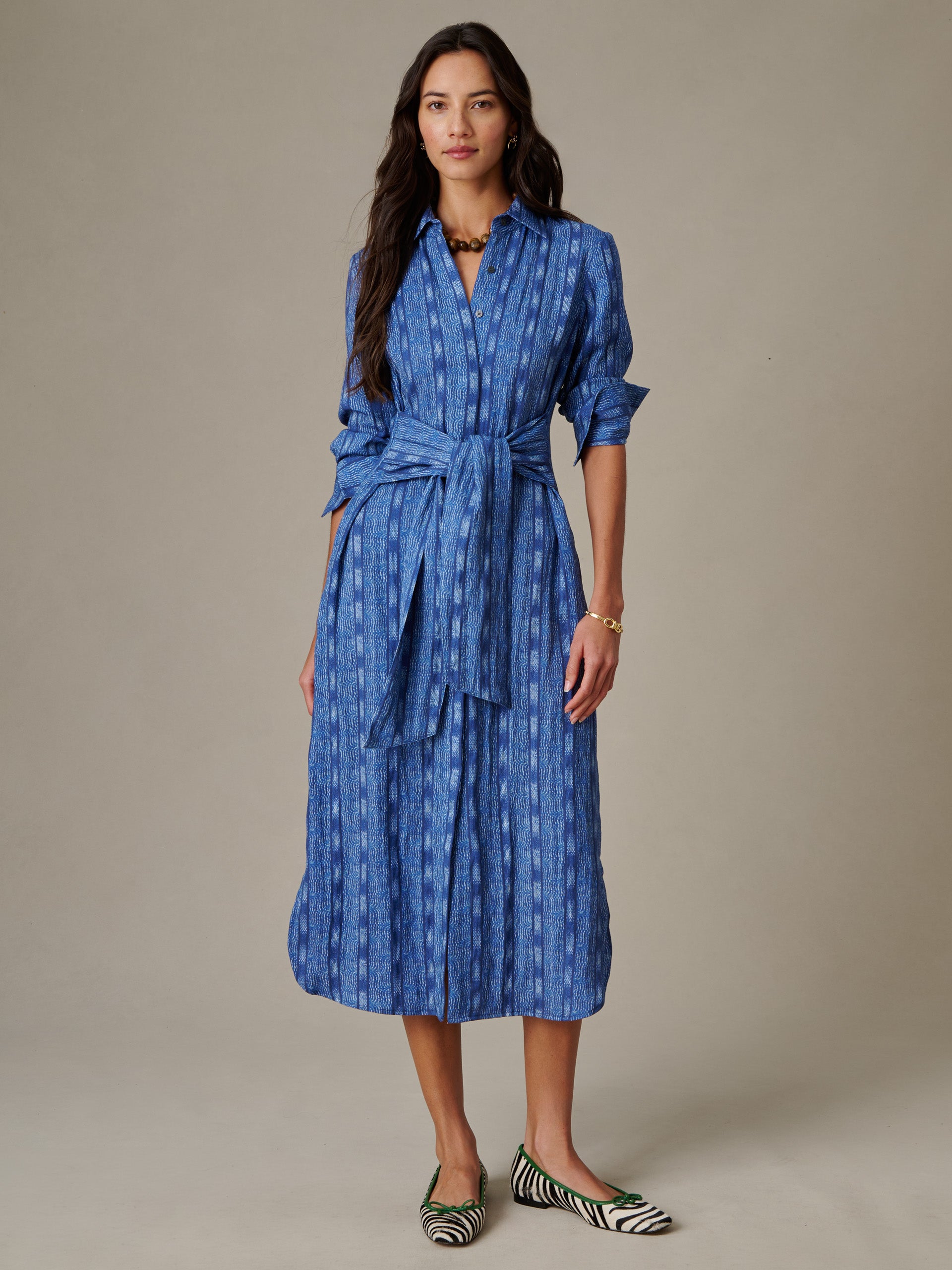 Woman wearing a blue Orla Dress in Wavelength by J.McLaughlin featuring a collar, button-down front, belted waist, and three-quarter sleeves, styled with striped flats.