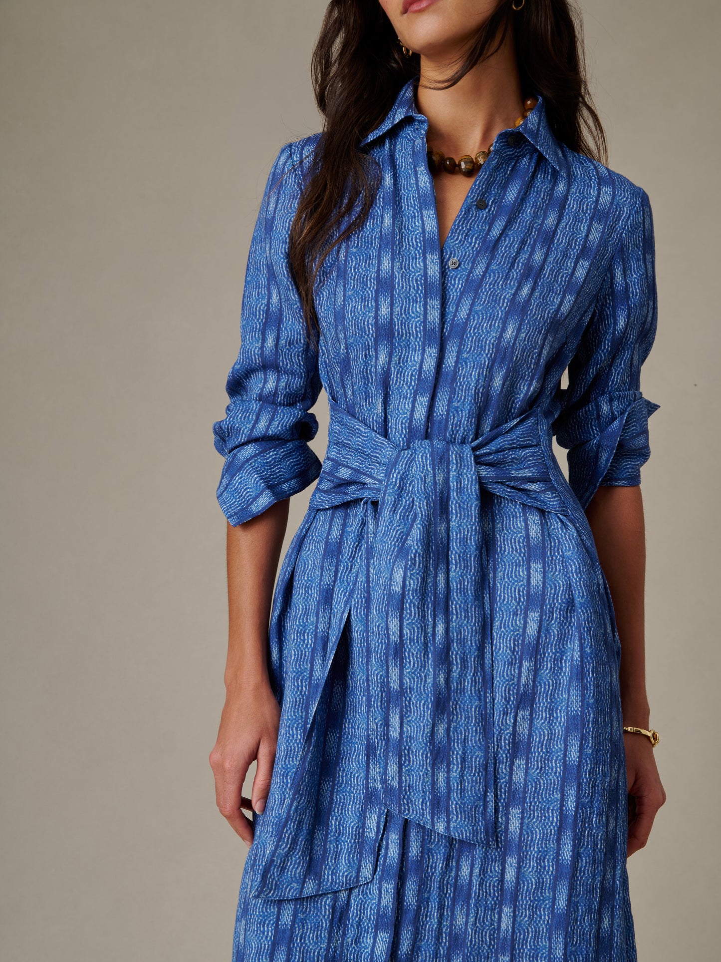 Close-up of a woman wearing the Orla Dress in Wavelength by J.McLaughlin, featuring a blue patterned fabric, button-up front, and tied waist belt, showcasing timeless style and quality craftsmanship.