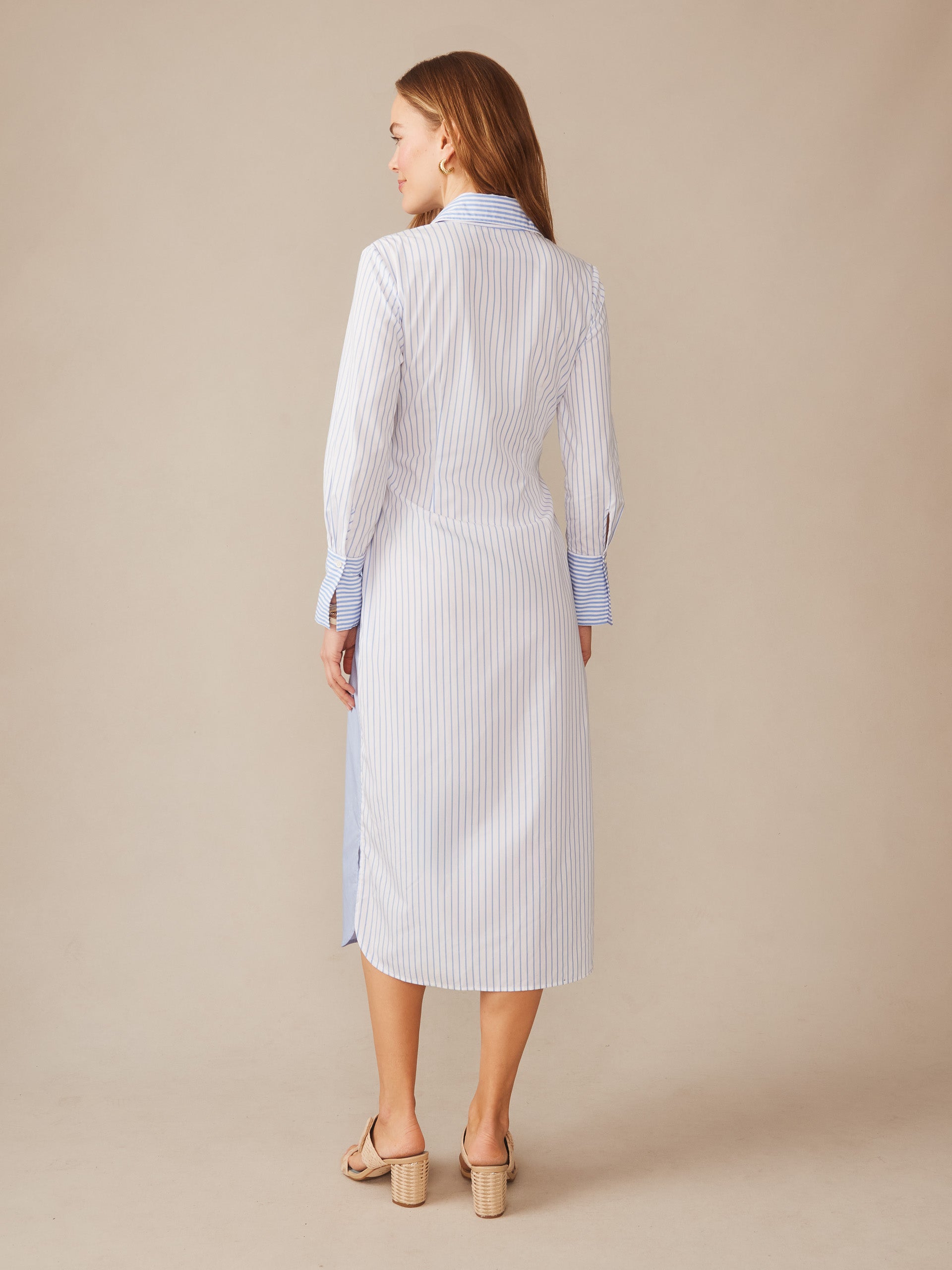 Woman seen from behind wearing the Orla Dress in Stripe by J.McLaughlin, featuring a classic striped pattern in white and blue, epitomizing effortlessly stylish, enduring designs with innovative fabrics in a legacy of timeless fashion. A destination for defining style. Life, Well-Lived.