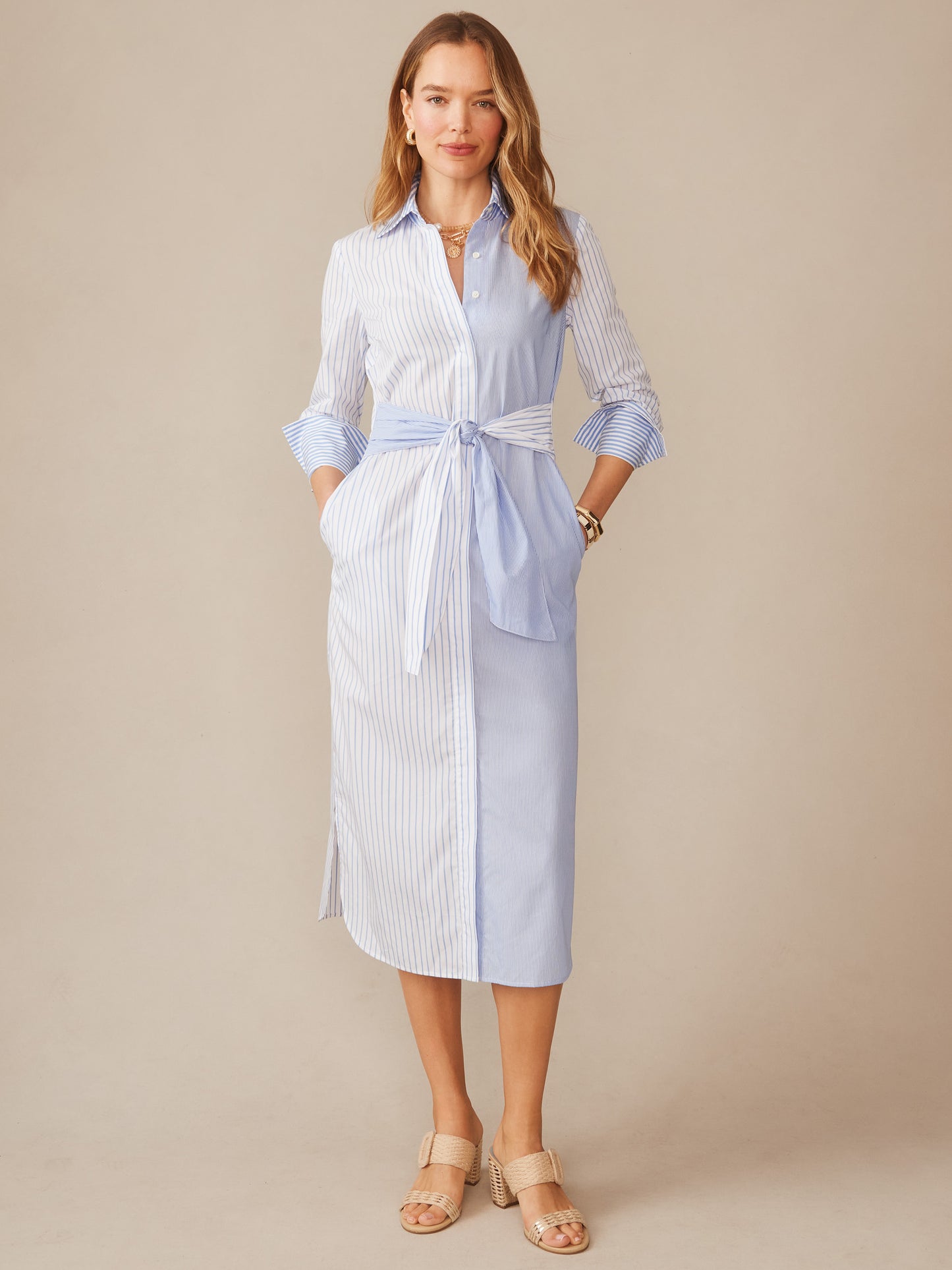 Woman wearing the Orla Dress in Stripe by J.McLaughlin, featuring a blue and white striped shirt dress with tie waist, embodying effortlessly stylish, enduring designs and innovative fabrics.