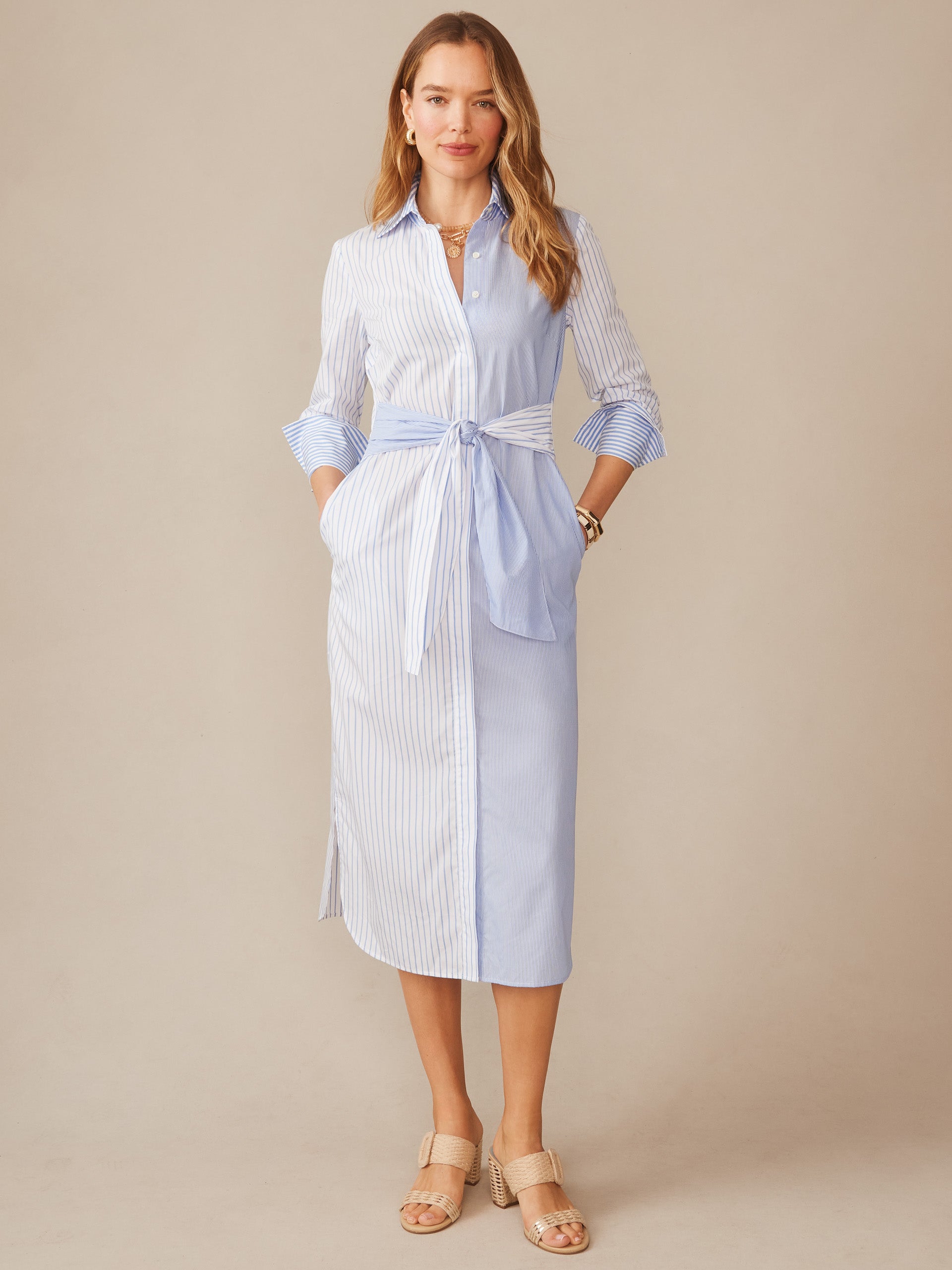 Woman wearing the Orla Dress in Stripe by J.McLaughlin, featuring a blue and white striped shirt dress with tie waist, embodying effortlessly stylish, enduring designs and innovative fabrics.