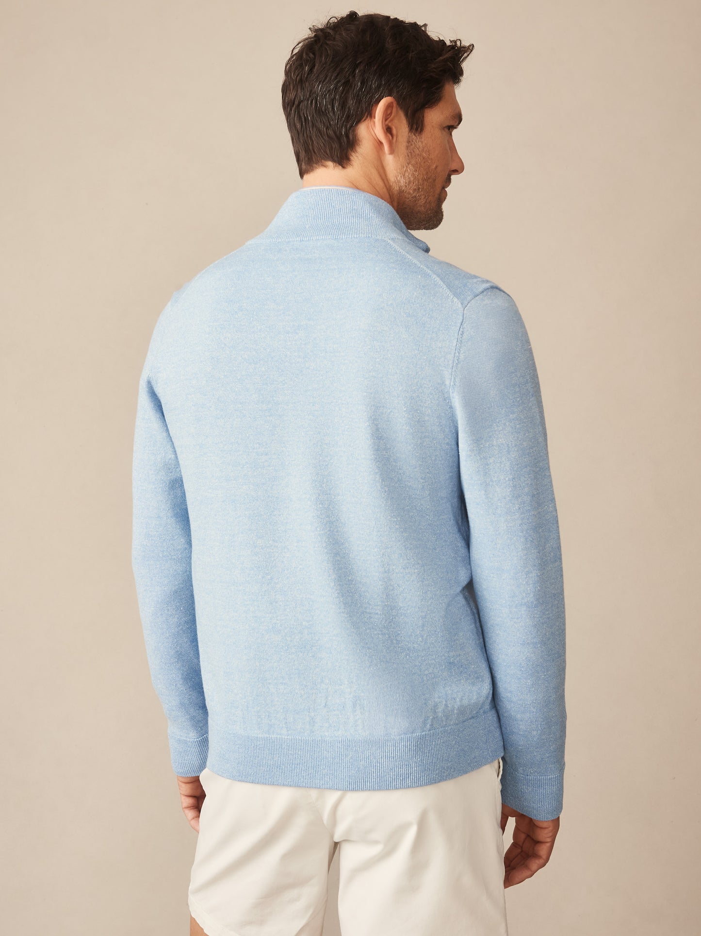 Man wearing a light blue Orwell Sweater by J.McLaughlin, showcasing effortlessly stylish and enduring designs with innovative fabrics in a timeless, classic look.