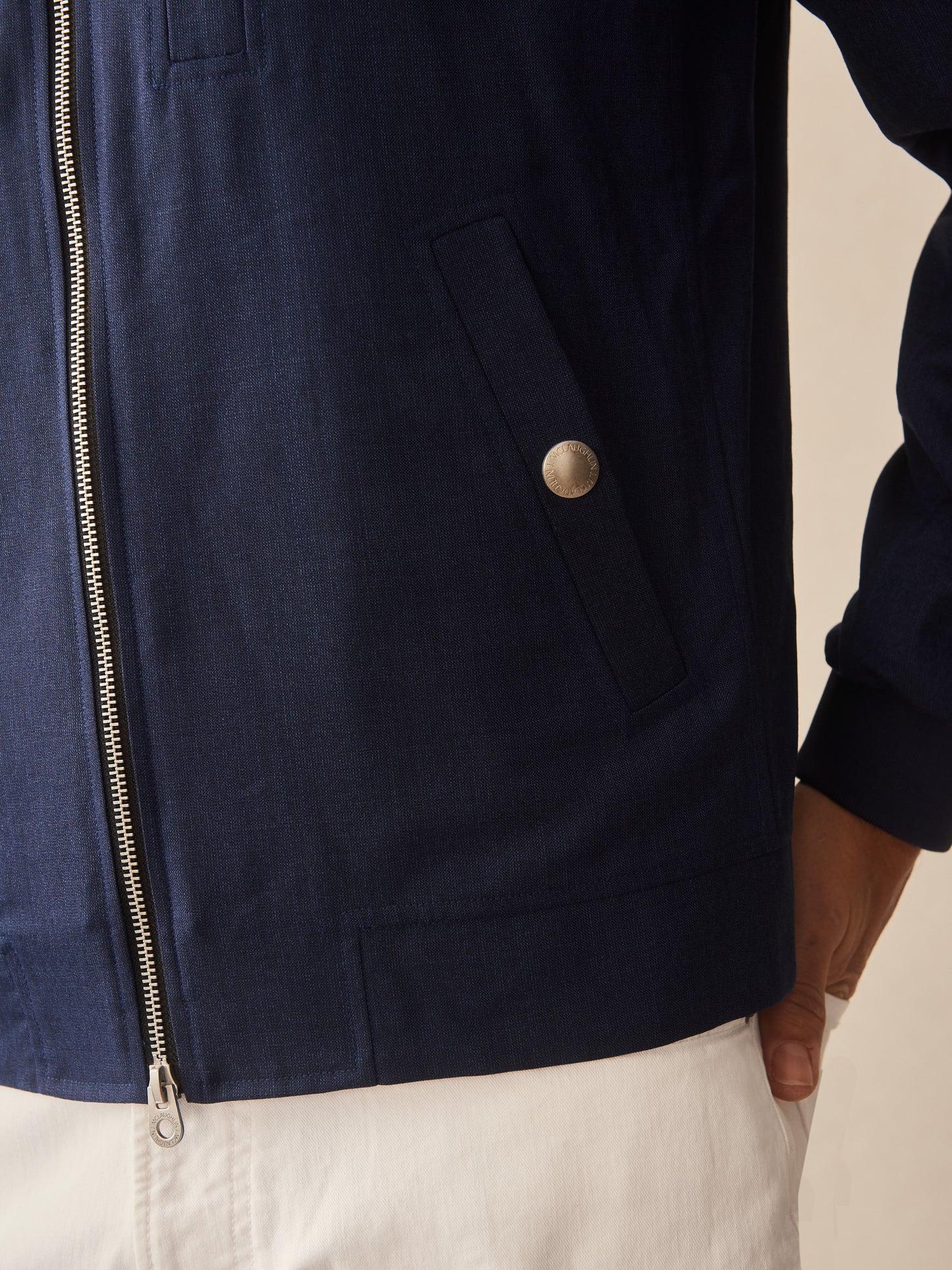 Close-up of a navy Outfield Jacket by J.McLaughlin, showcasing meticulously crafted pockets and zipper, reflecting effortlessly stylish, enduring designs in innovative fabrics.