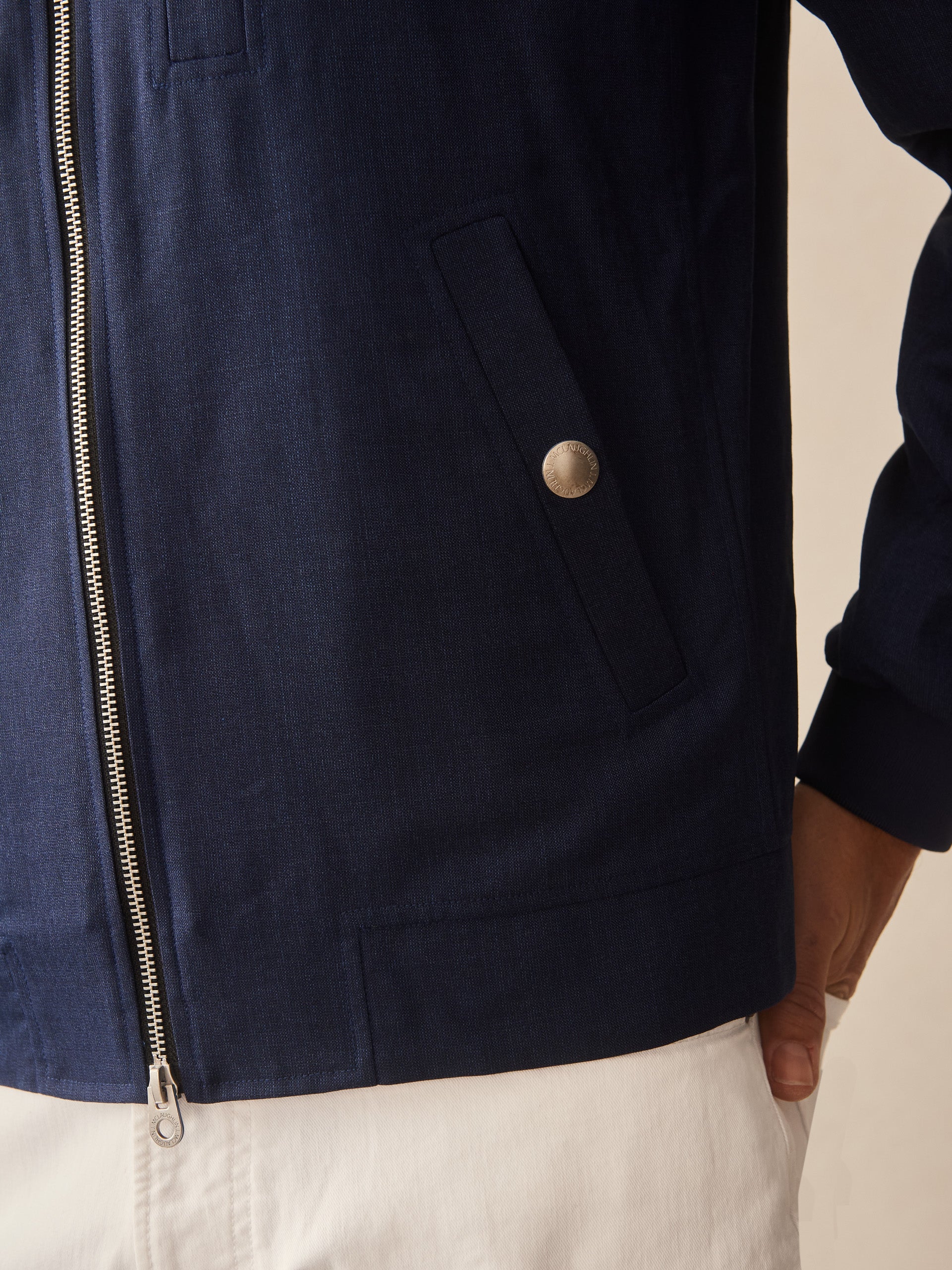 Close-up of a navy Outfield Jacket by J.McLaughlin, showcasing meticulously crafted pockets and zipper, reflecting effortlessly stylish, enduring designs in innovative fabrics.