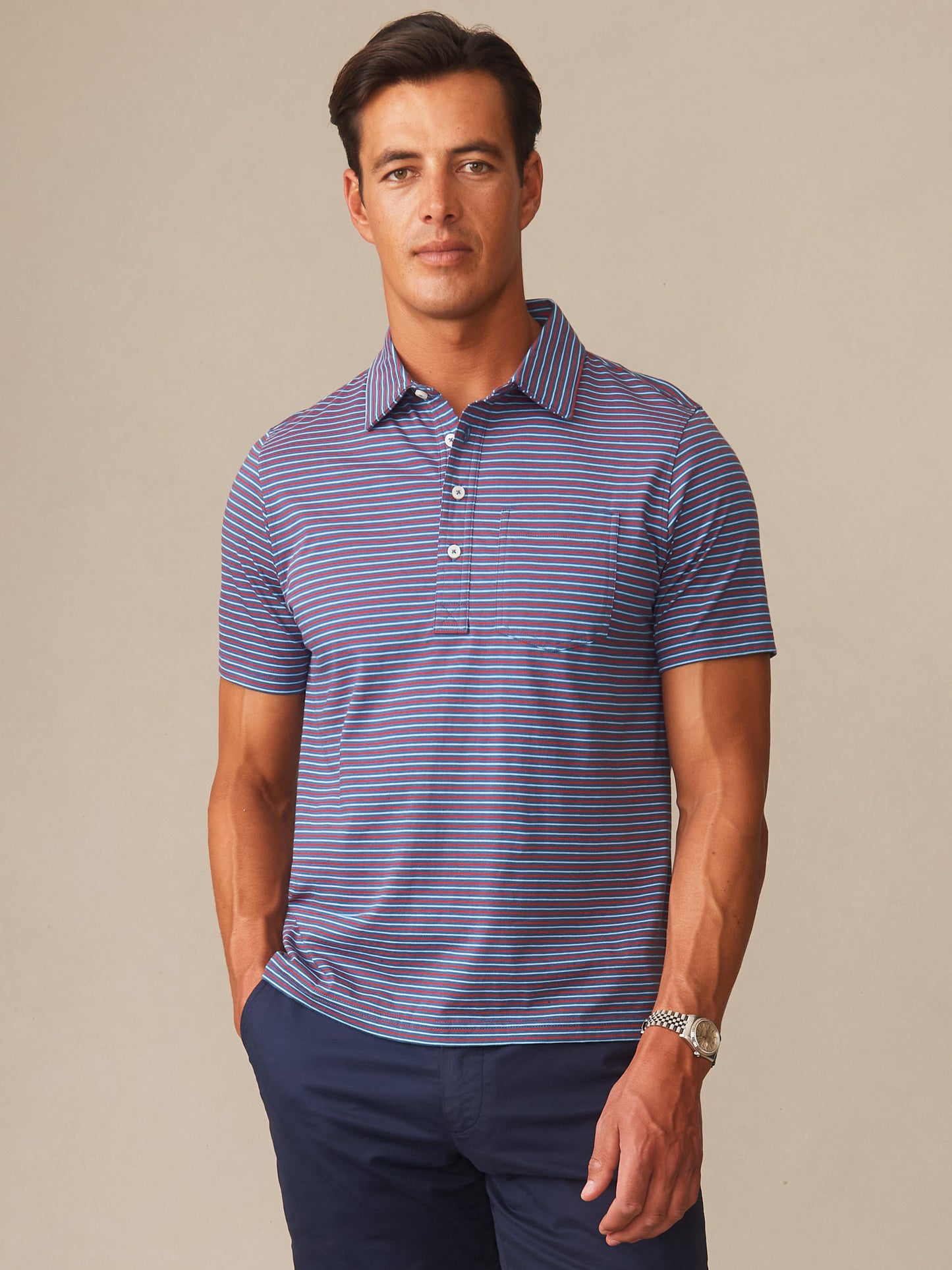 Man wearing Owens Polo in Multi Stripe Tricolor by J.McLaughlin featuring blue, red, and white stripes, showcasing effortlessly stylish, enduring designs with a legacy of timeless fashion.