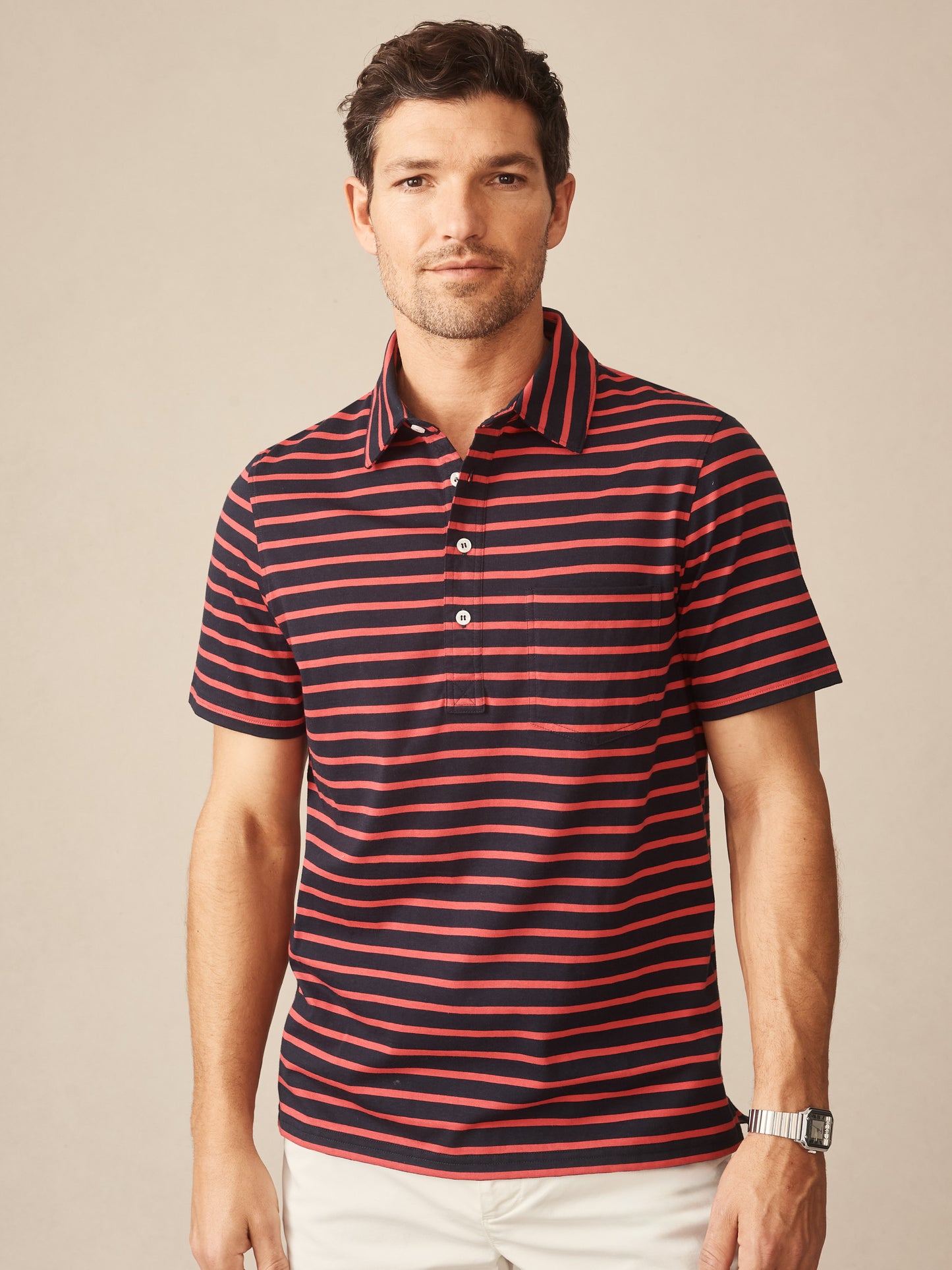Man wearing an effortlessly stylish Owens Polo in Breton Stripe by J.McLaughlin, featuring navy and red stripes, showcasing enduring designs and innovative fabrics for a life well-lived.