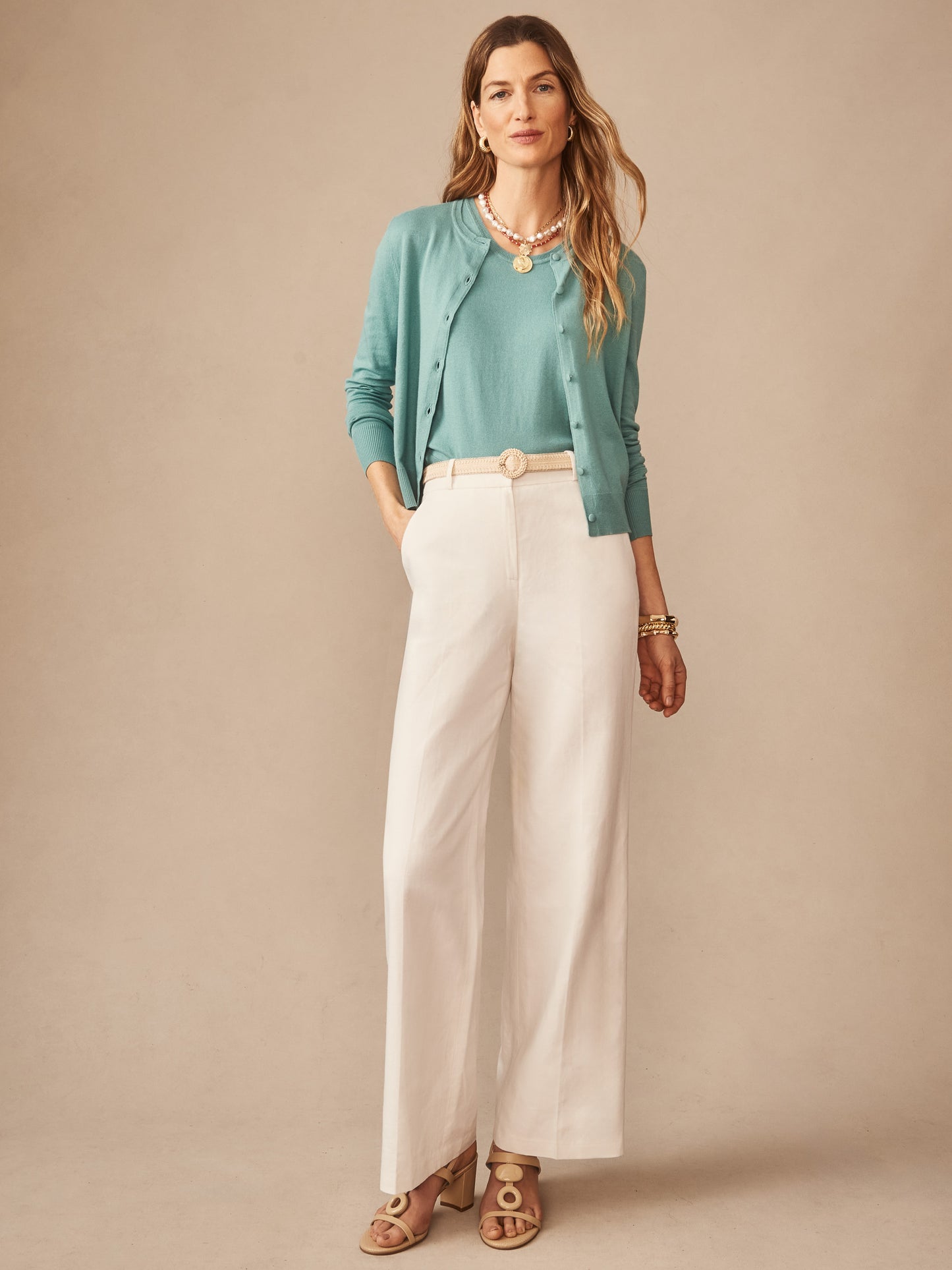 Woman wearing an effortlessly stylish turquoise Opal Sweater Tank by J.McLaughlin paired with cream wide-leg pants, showcasing enduring designs and innovative fabrics in a timeless look.