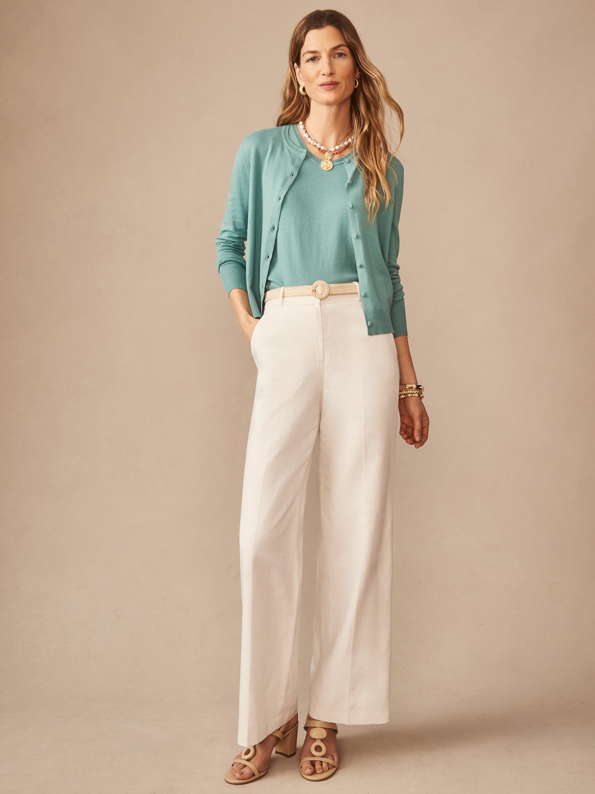 Woman wearing an effortlessly stylish turquoise Opal Sweater Tank by J.McLaughlin paired with cream wide-leg pants, showcasing enduring designs and innovative fabrics in a timeless look.