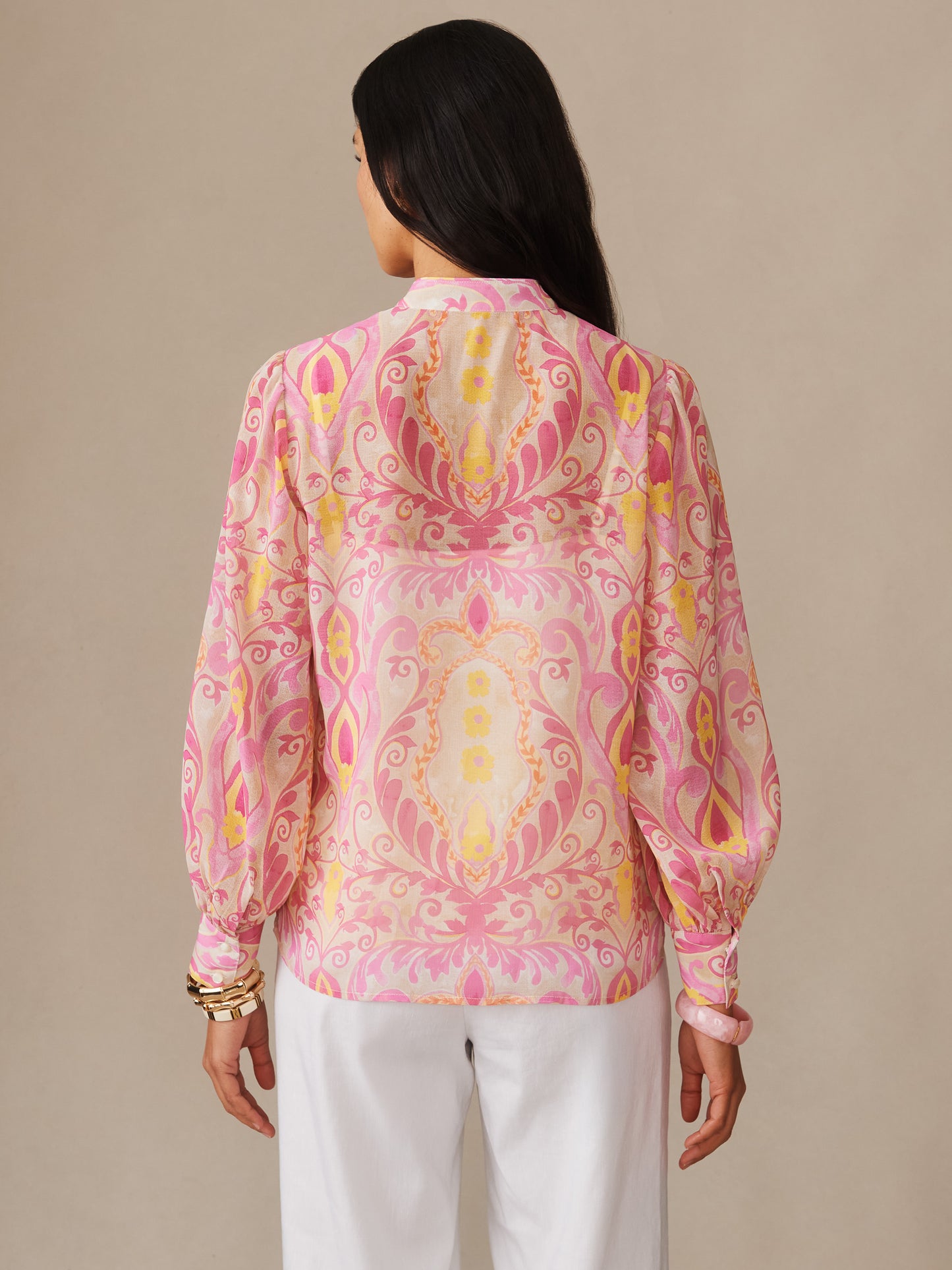 Woman wearing the Peyton Blouse in Mini Deco Bloom by J.McLaughlin, showcasing its effortlessly stylish, enduring designs with a vibrant pink and yellow pattern, embodying a legacy of timeless fashion. A destination for defining style. Life, Well-Lived.