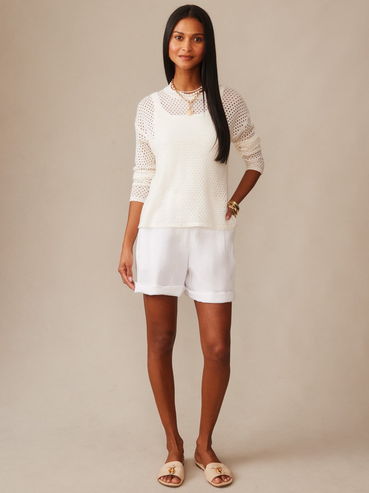 A woman wearing a white Philomena Cashmere Linen Sweater by J.McLaughlin, styled with white shorts and neutral sandals, showcasing effortlessly stylish, enduring designs crafted for timeless fashion.
