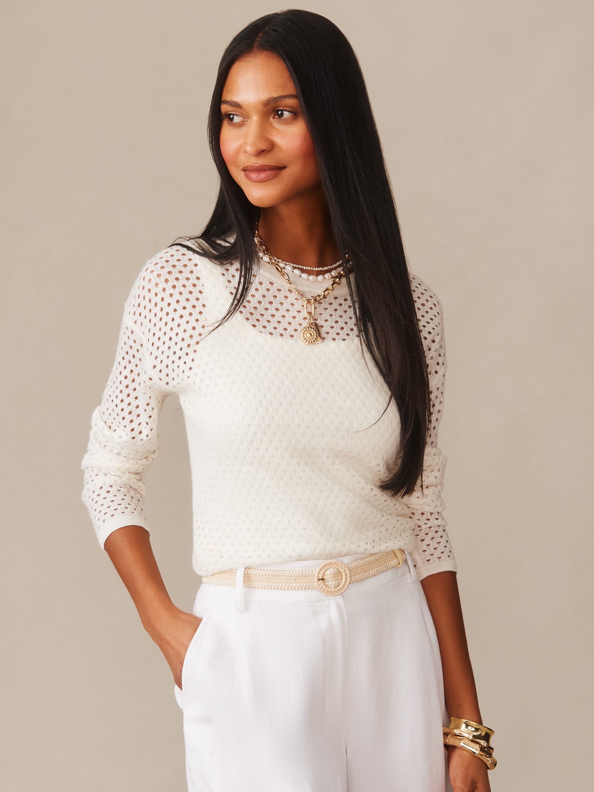 Woman wearing a white Philomena Cashmere Linen Sweater by J.McLaughlin, styled with white pants and layered gold jewelry, showcasing effortlessly stylish, enduring designs and innovative fabrics.