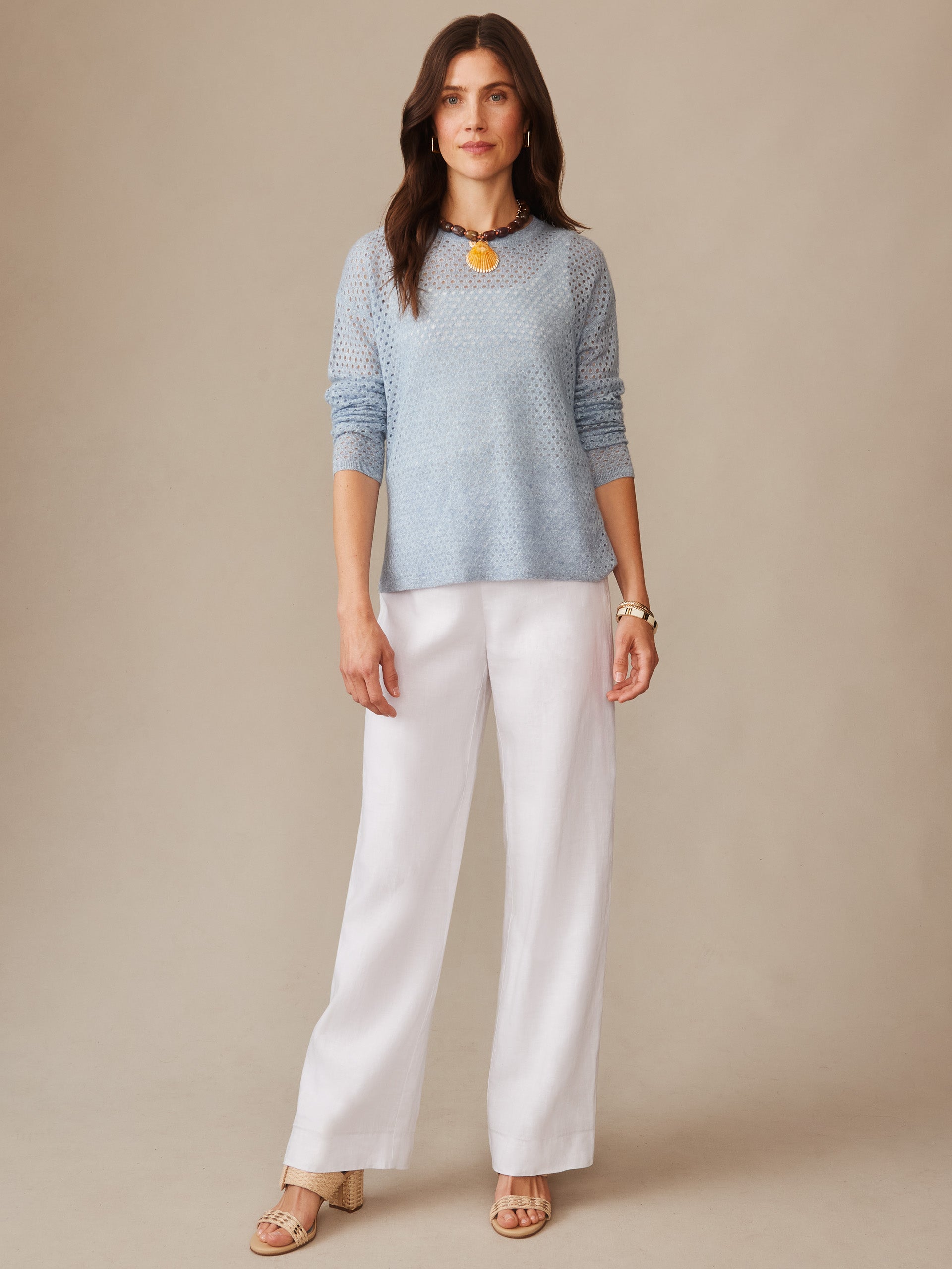 Woman wearing a light blue Philomena Cashmere Linen Sweater paired with white wide-leg pants and sandals, showcasing J.McLaughlin’s effortlessly stylish, enduring designs with innovative fabrics for a legacy of timeless fashion. A destination for defining style. Life, Well-Lived.