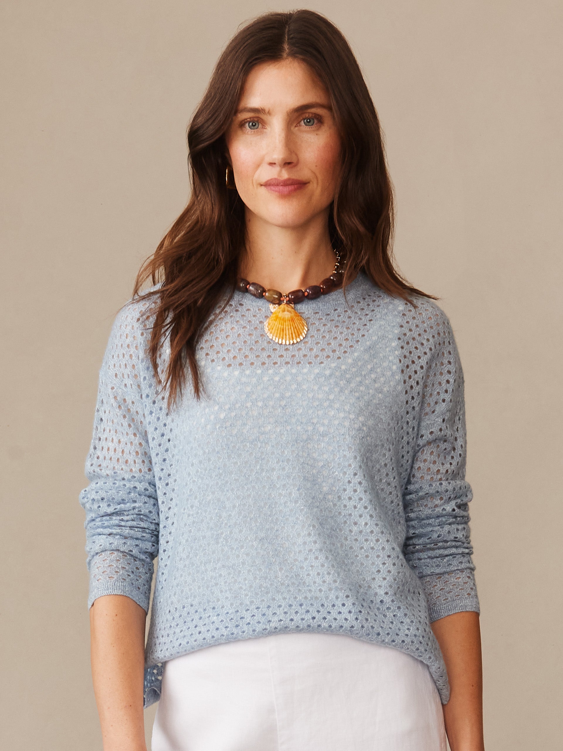 Woman wearing a light blue Philomena Cashmere Linen Sweater by J.McLaughlin, showcasing effortlessly stylish, enduring designs with a delicate knit texture and a statement necklace.