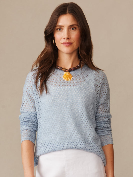 Woman wearing a light blue Philomena Cashmere Linen Sweater by J.McLaughlin, showcasing effortlessly stylish, enduring designs with a delicate knit texture and a statement necklace.