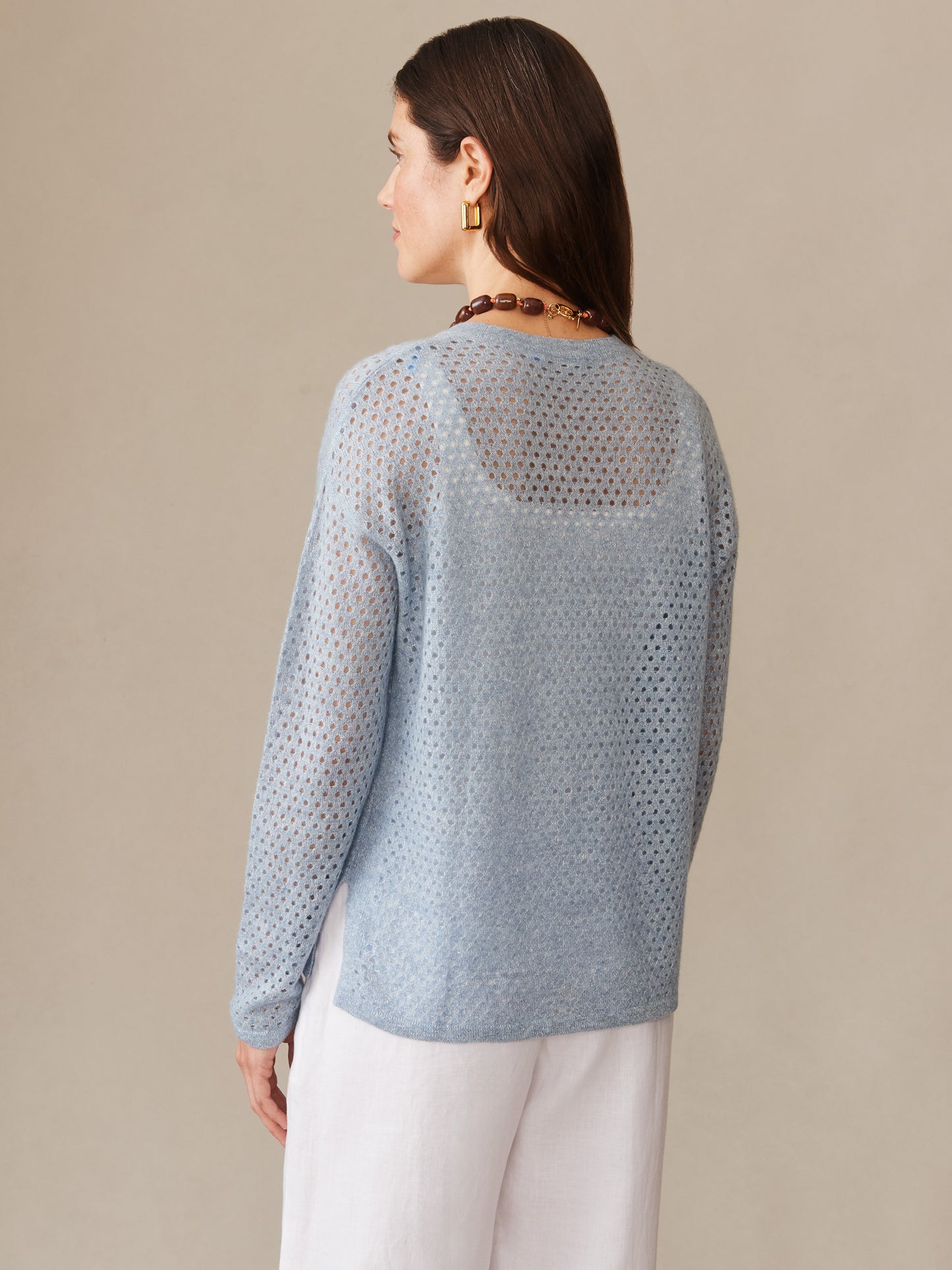 A woman wearing a light blue Philomena Cashmere Linen Sweater by J.McLaughlin, showcasing an effortlessly stylish, breathable knit design, perfect for enduring designs and innovative fabrics.