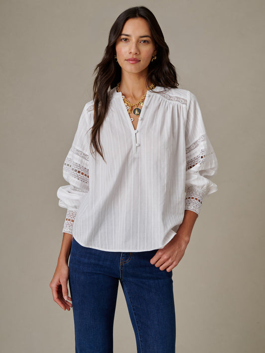 Woman wearing a white Posey Blouse by J.McLaughlin featuring delicate lace details on the sleeves, combining effortless style with timeless elegance.