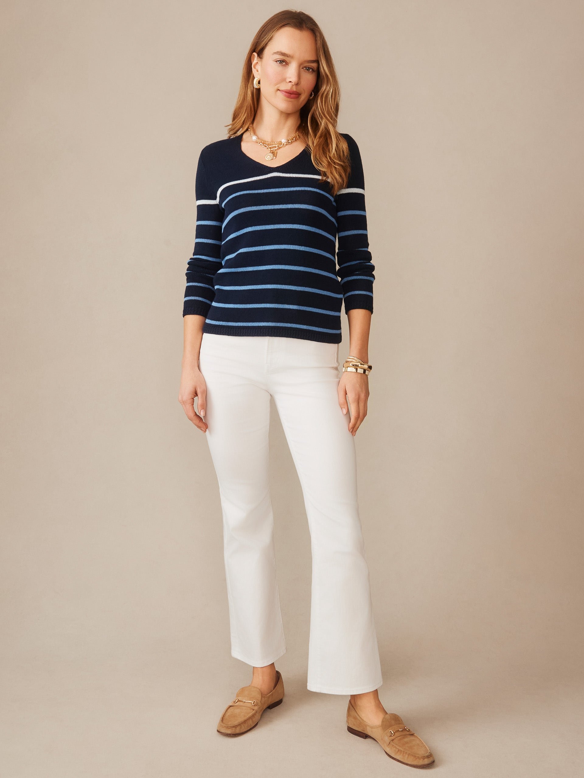Woman wearing a Ramona Linen Blend Sweater in Stripe by J.McLaughlin, styled with white pants and loafers, showcasing effortlessly stylish, enduring designs and innovative fabrics.