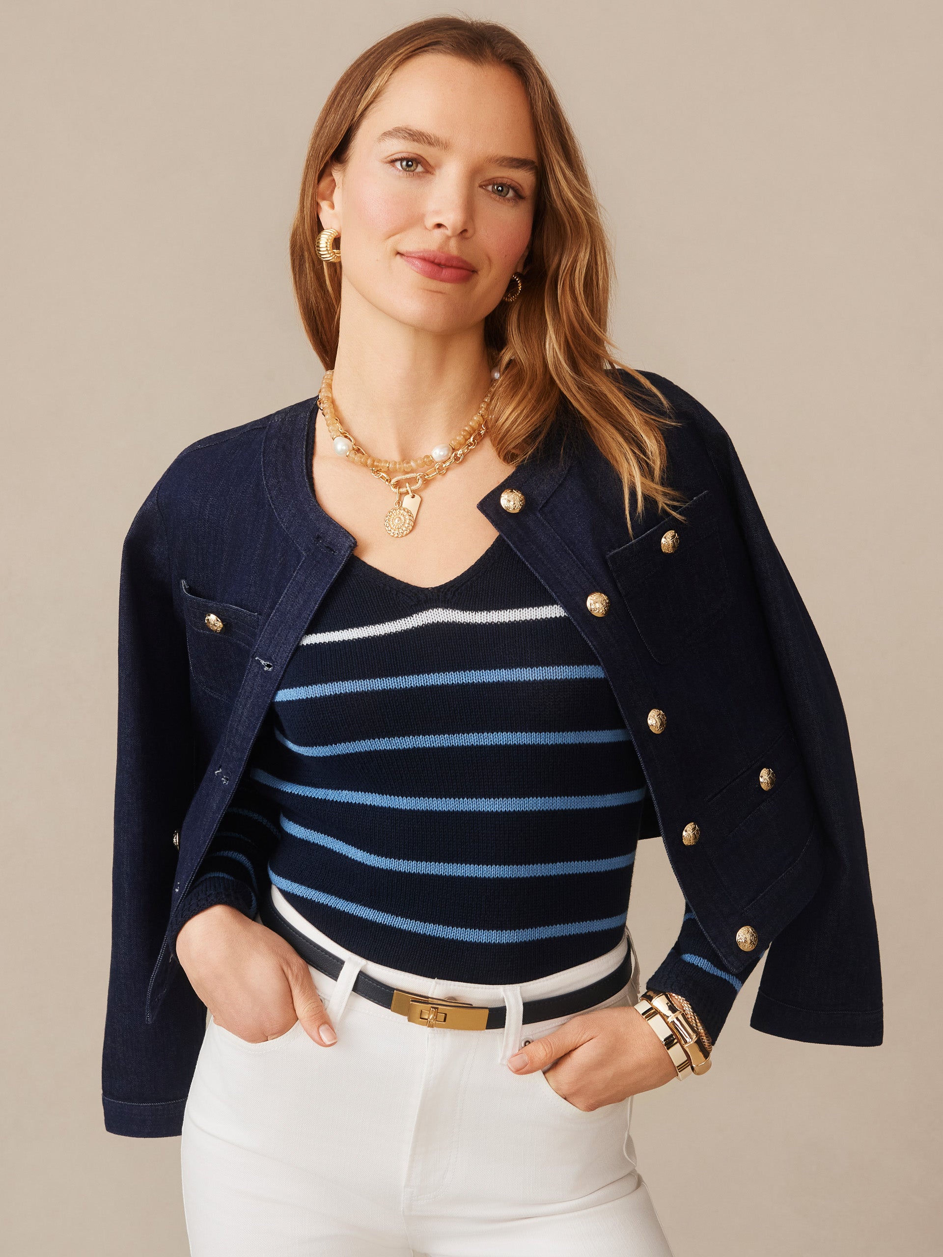 Woman wearing a Ramona Linen Blend Sweater in Stripe by J.McLaughlin with a navy jacket draped over her shoulders, accessorized with gold jewelry and white pants, showcasing effortlessly stylish, enduring designs and innovative fabrics at a destination for defining style. Life, Well-Lived.