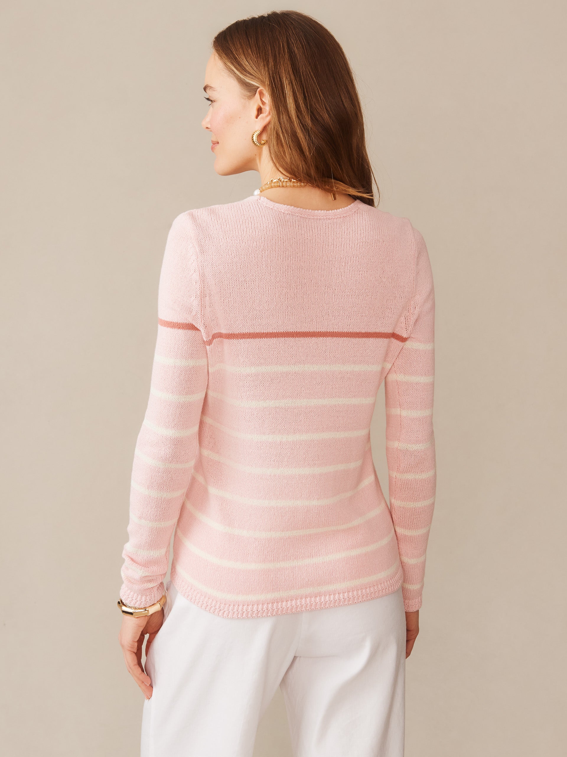 A woman seen from behind wearing the Ramona Linen Blend Sweater in Stripe by J.McLaughlin with soft pink and white horizontal stripes, showcasing effortlessly stylish, enduring designs with innovative fabrics for a legacy of timeless fashion. A destination for defining style. Life, Well-Lived.