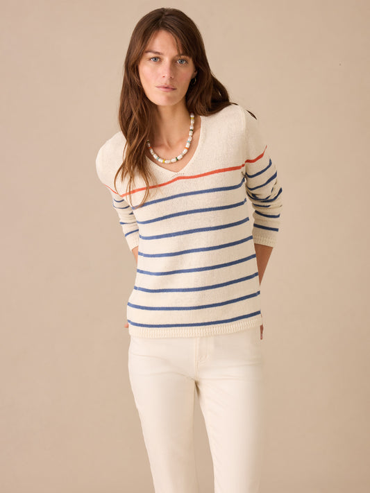 Woman wearing J.McLaughlin Ramona Linen Blend Sweater in Stripe with blue and coral stripes, paired with white pants, showcasing effortlessly stylish, enduring designs and innovative fabrics.
