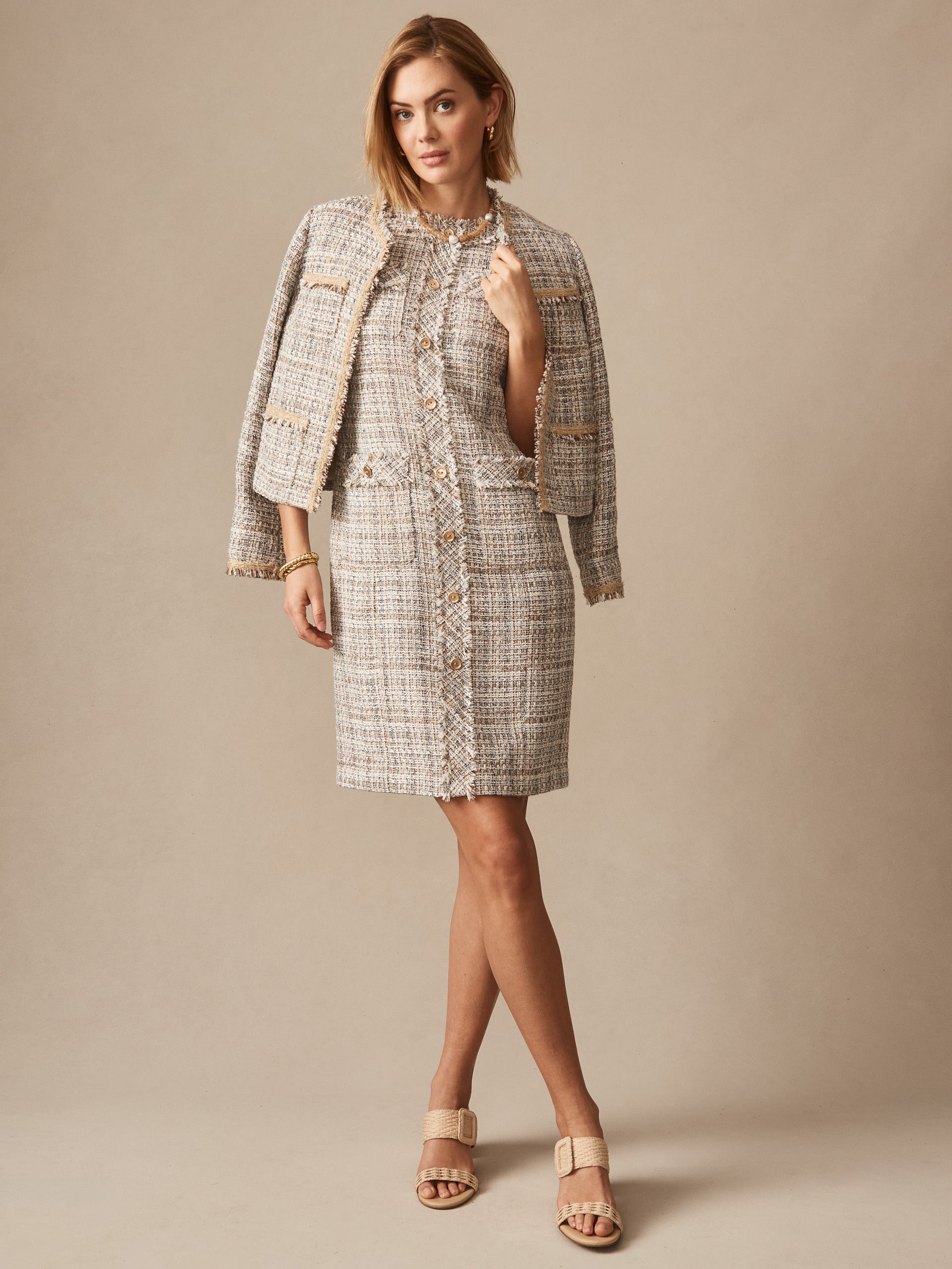 Woman wearing the Regina Tweed Dress by J.McLaughlin paired with a matching tweed jacket draped over her shoulders, showcasing effortlessly stylish and enduring designs in soft taupe and off-white hues.