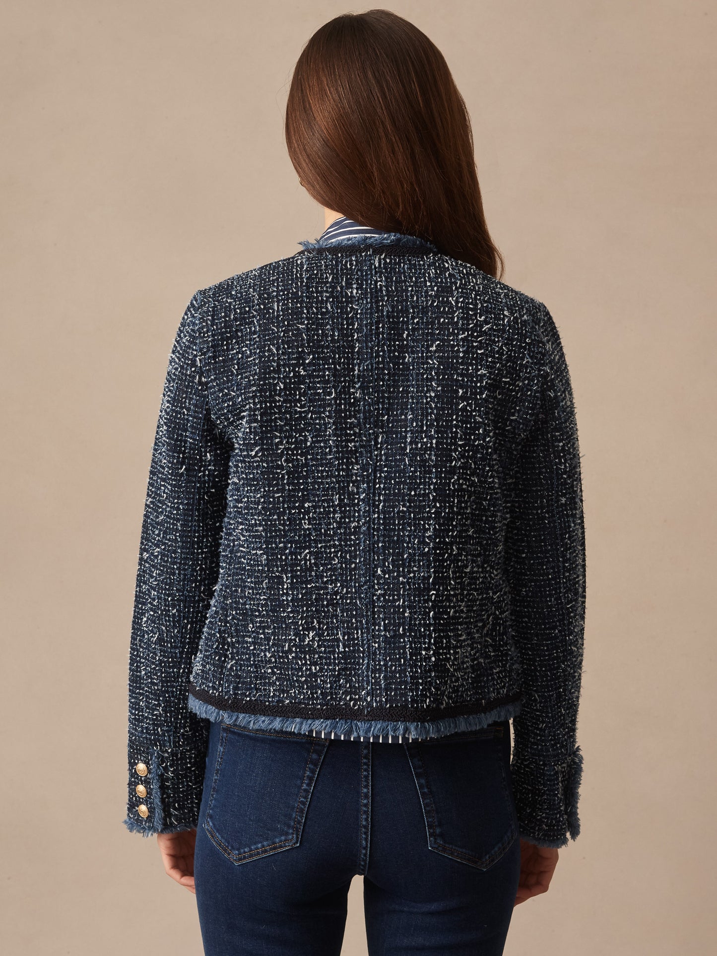 Woman modeling the Renata Jacket by J.McLaughlin, featuring effortlessly stylish textured fabric with fringe trim details and gold button accents, exemplifying enduring designs and innovative fabrics.