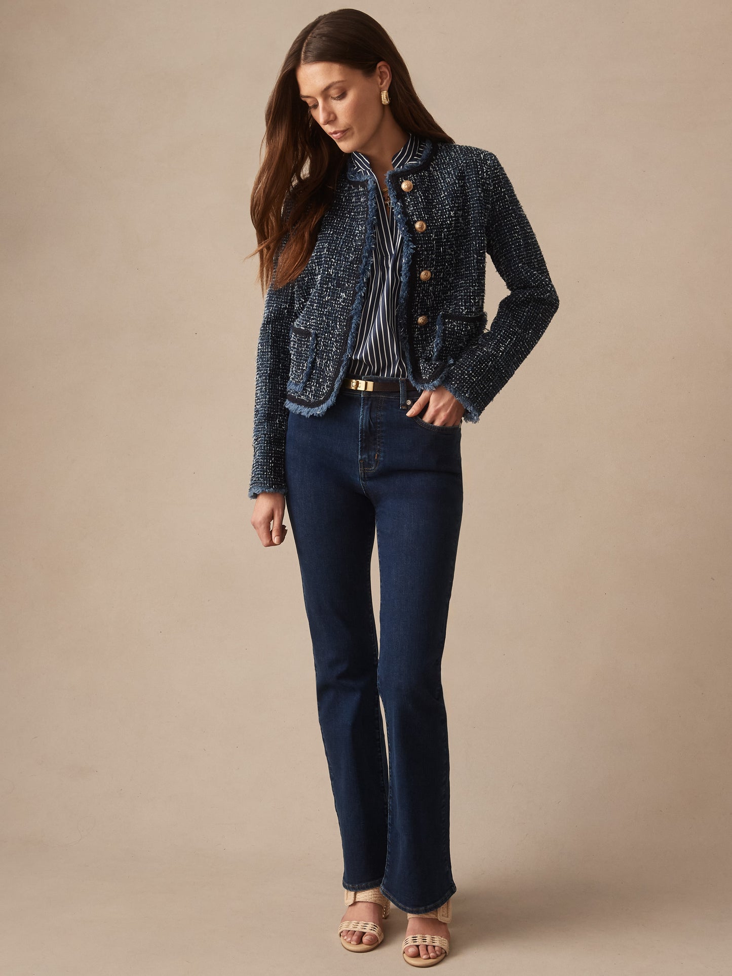 Woman wearing a J.McLaughlin Renata Jacket over a striped blouse paired with dark denim jeans and sandals, showcasing effortlessly stylish, enduring designs in innovative fabrics.