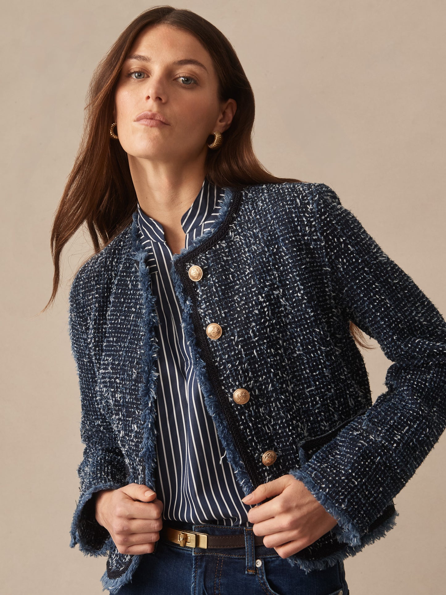 A woman models the Renata Jacket by J.McLaughlin, a chic and effortlessly stylish navy textured jacket with gold buttons, embodying enduring designs and a legacy of timeless fashion.