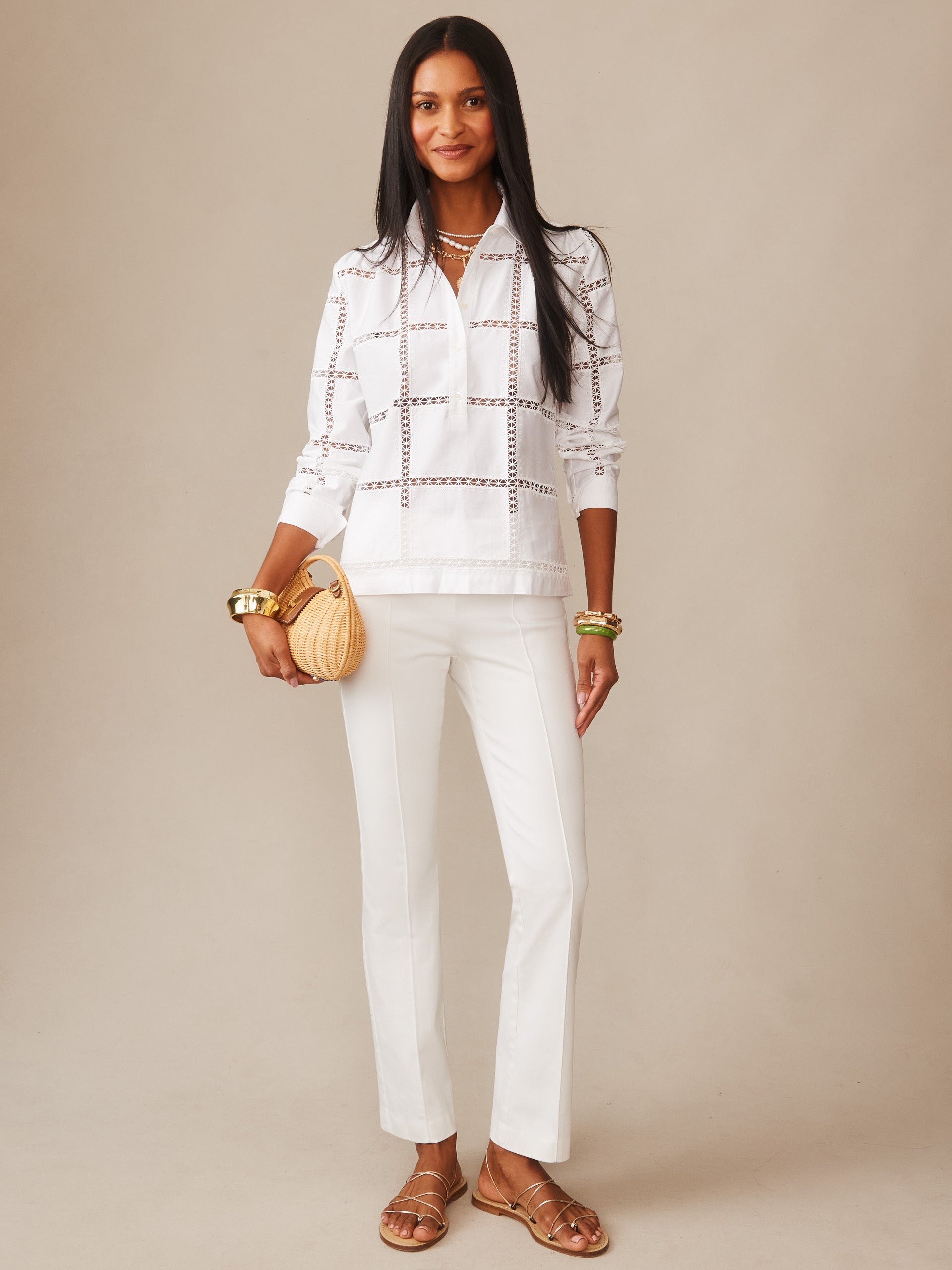 A stylish woman wearing crisp white Rylie Jeans by J.McLaughlin paired with a patterned white top, accessorized with gold bracelets and a woven handbag, embodying effortlessly stylish and enduring designs from a legacy of timeless fashion at a destination for defining style. Life, Well-Lived.